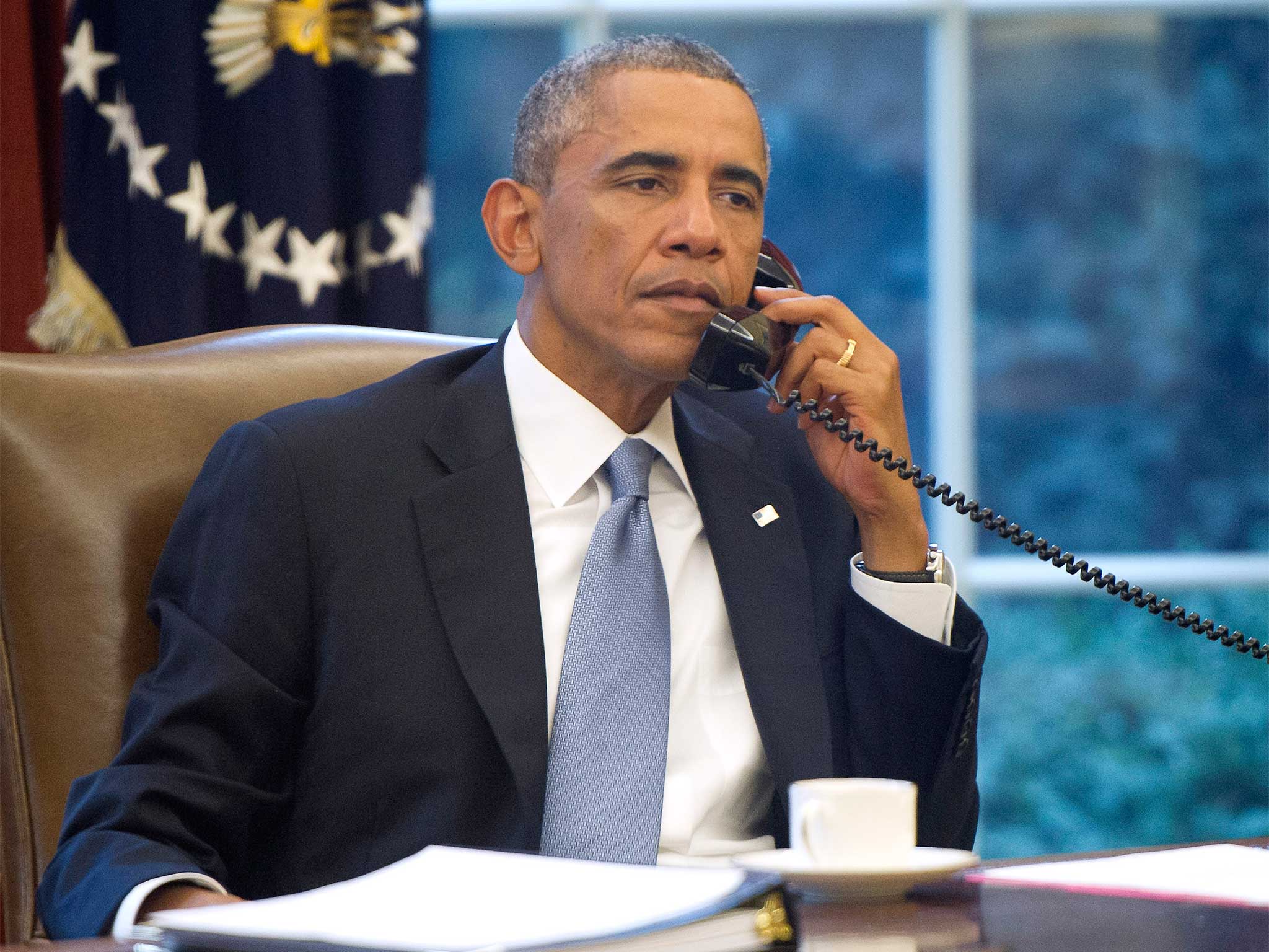 President Obama, seen through an Oval Office window, speaks on the phone with King Abdallah Abd al Aziz of the Kingdom of Saudi Arabia on 10 September 2014 ahead of his speech on the Islamic State to the nation