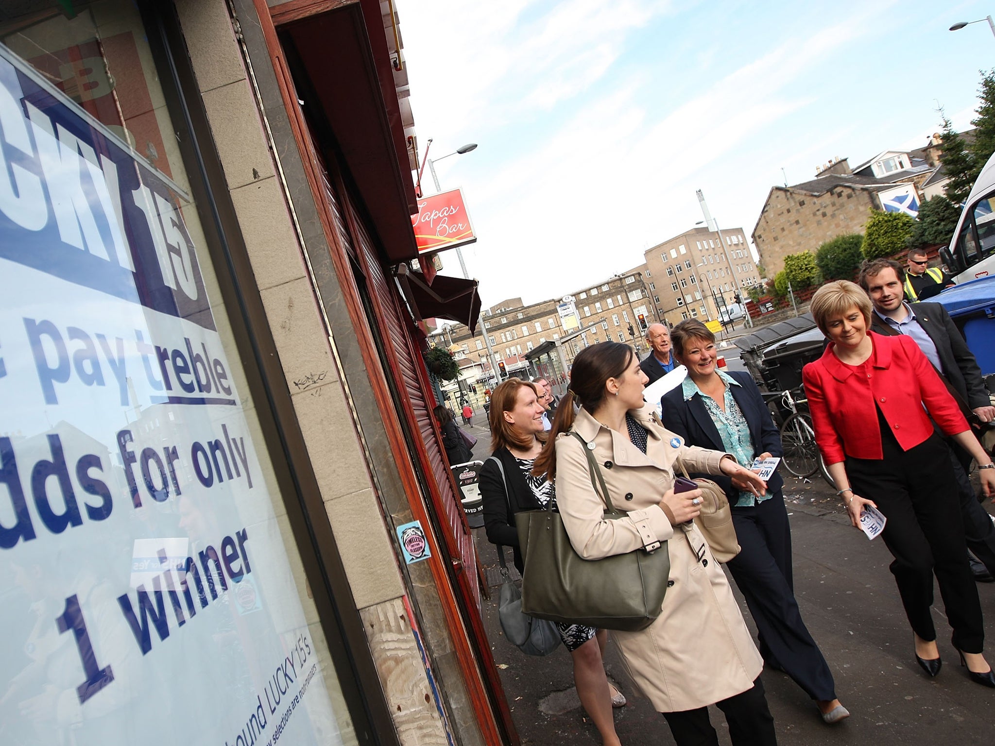 The Deputy First Minister of Scotland, Nicola Sturgeon (right), is joined by the leader of Welsh nationalist party Plaid Cymru Leanne Wood (centre) as they pass a bookmakers
during a walk-about to meet the Scottish electorate