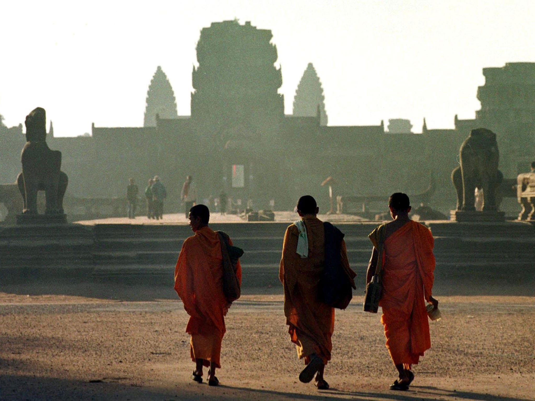 Cambodian monks stroll through Angkor Wat temple at sunset in Siem Reap.