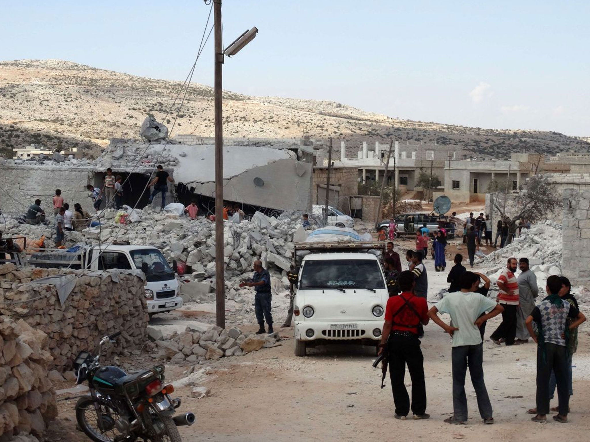 Syrians check a damaged house, reportedly hit by US-led coalition air strikes, in the village of Kfar Derian in the western Aleppo province