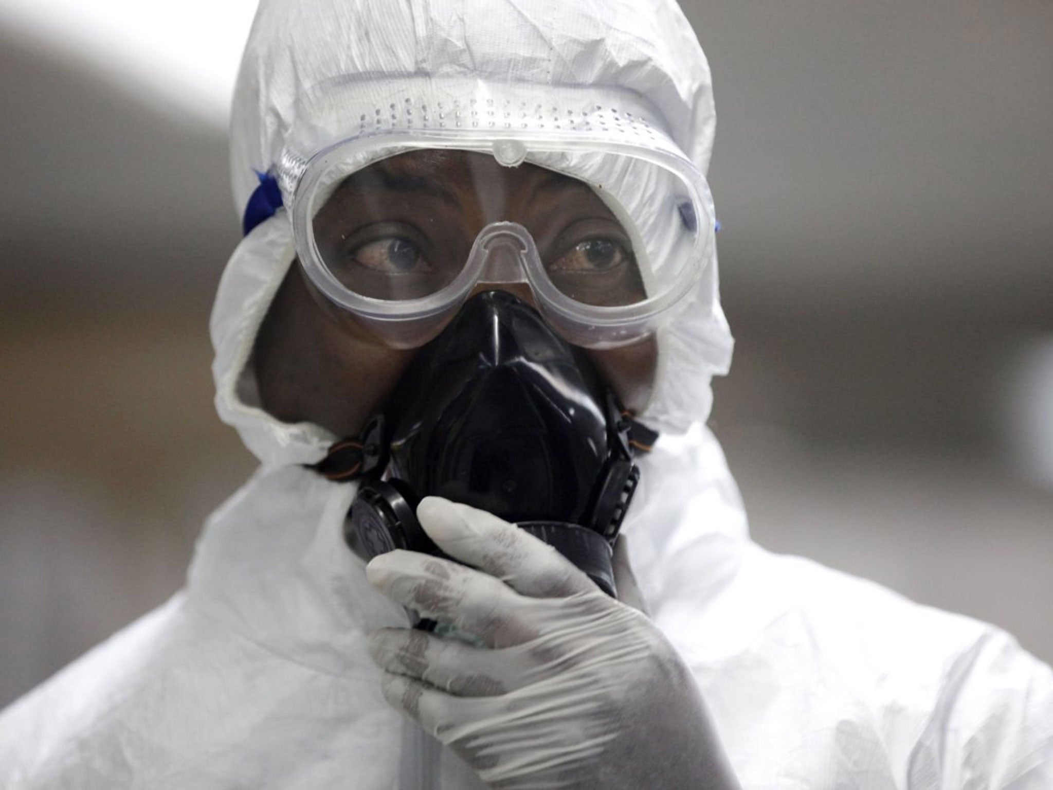 Nigerian health official wearing a protective suit waits to screen passengers for the Ebola virus at the arrivals hall of Murtala Muhammed International Airport in Lagos, Nigeria.