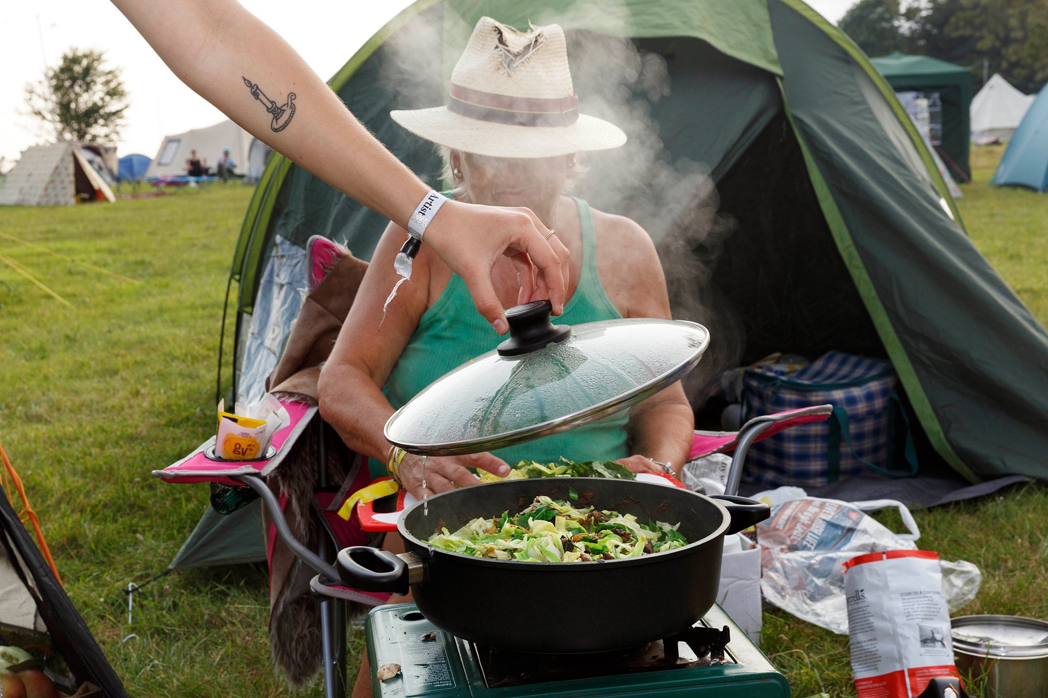 Lyn Pollard washes greens in preparation for a stew outside her tent at the Port Eliot festival in Cornwall. Camping and preparing food outdoors are two long-standing British traditions. In this case Lyn is cooking for her daughter and her girlfriends on