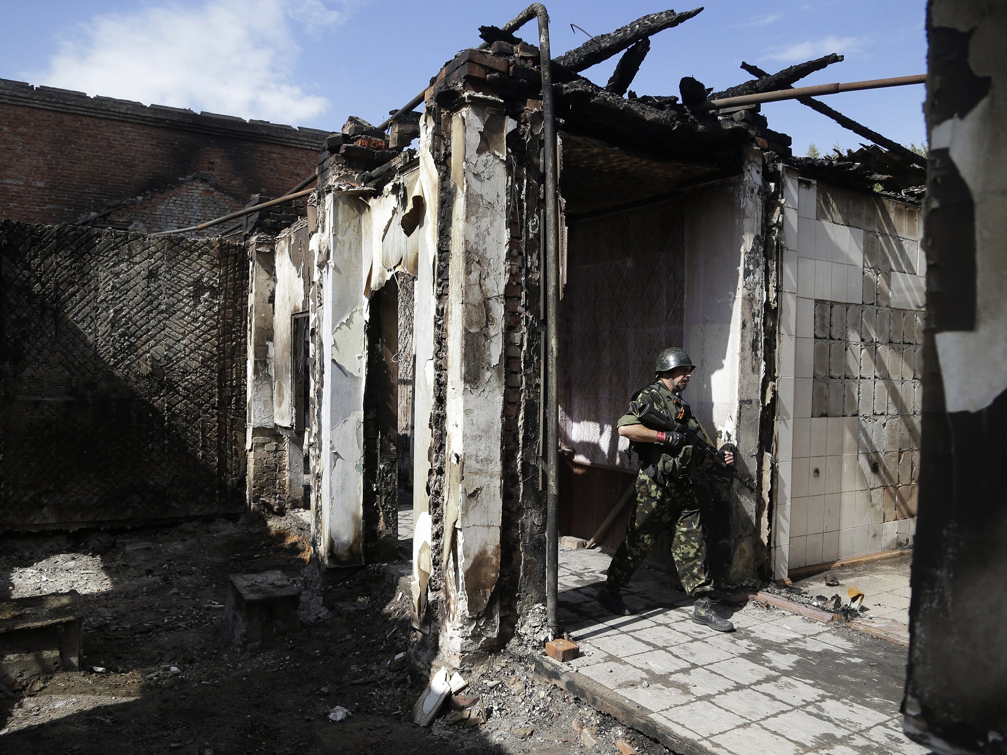 A pro-Russian rebel walks among the ruins of a mine entrance in Donetsk, where artillery fire can still be heard despite the recent ceasefire