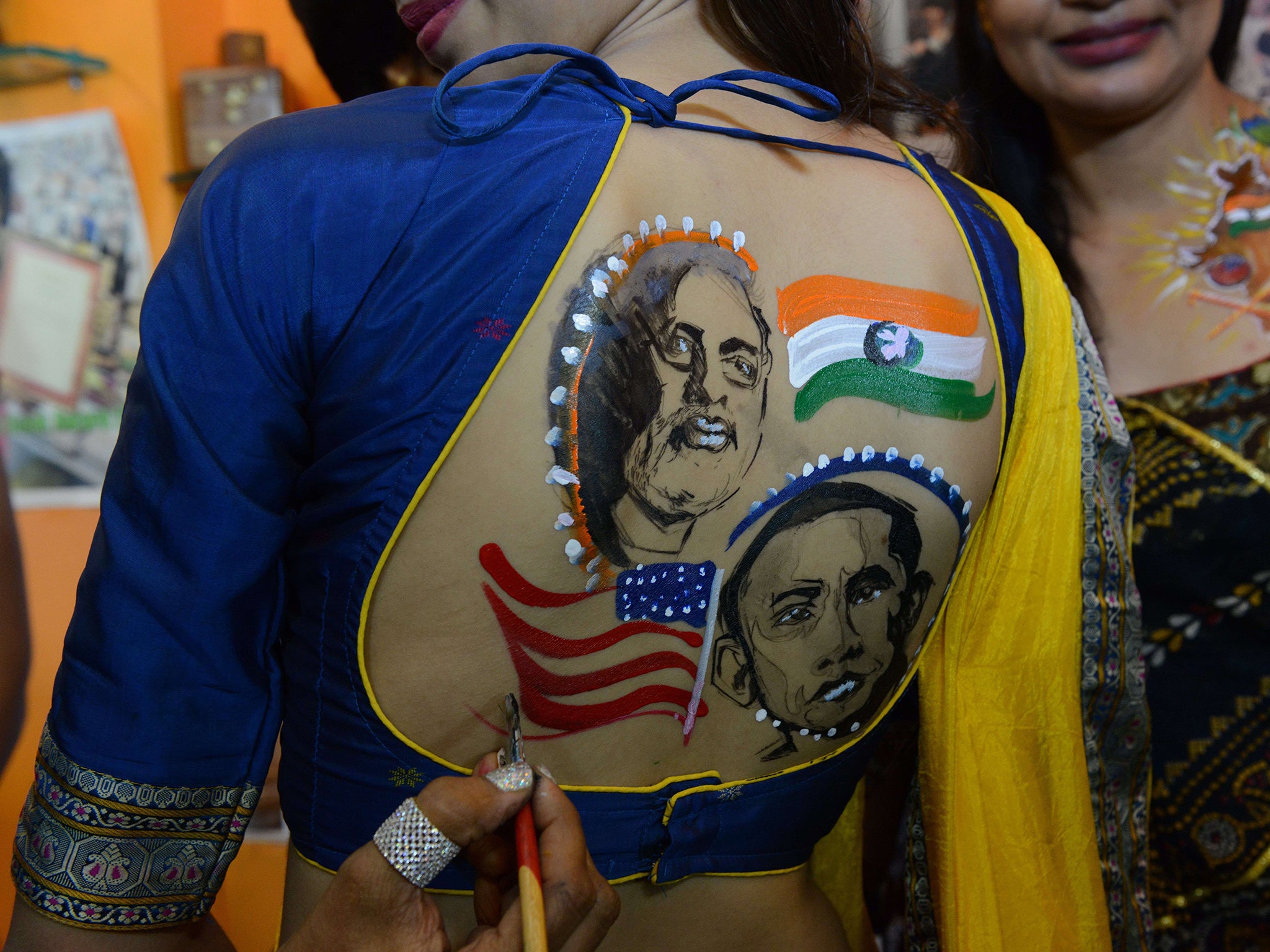 A tattoo artist paints portraits of US President Barack Obama and Indian Prime Minister Narendra Modi onto women's backs