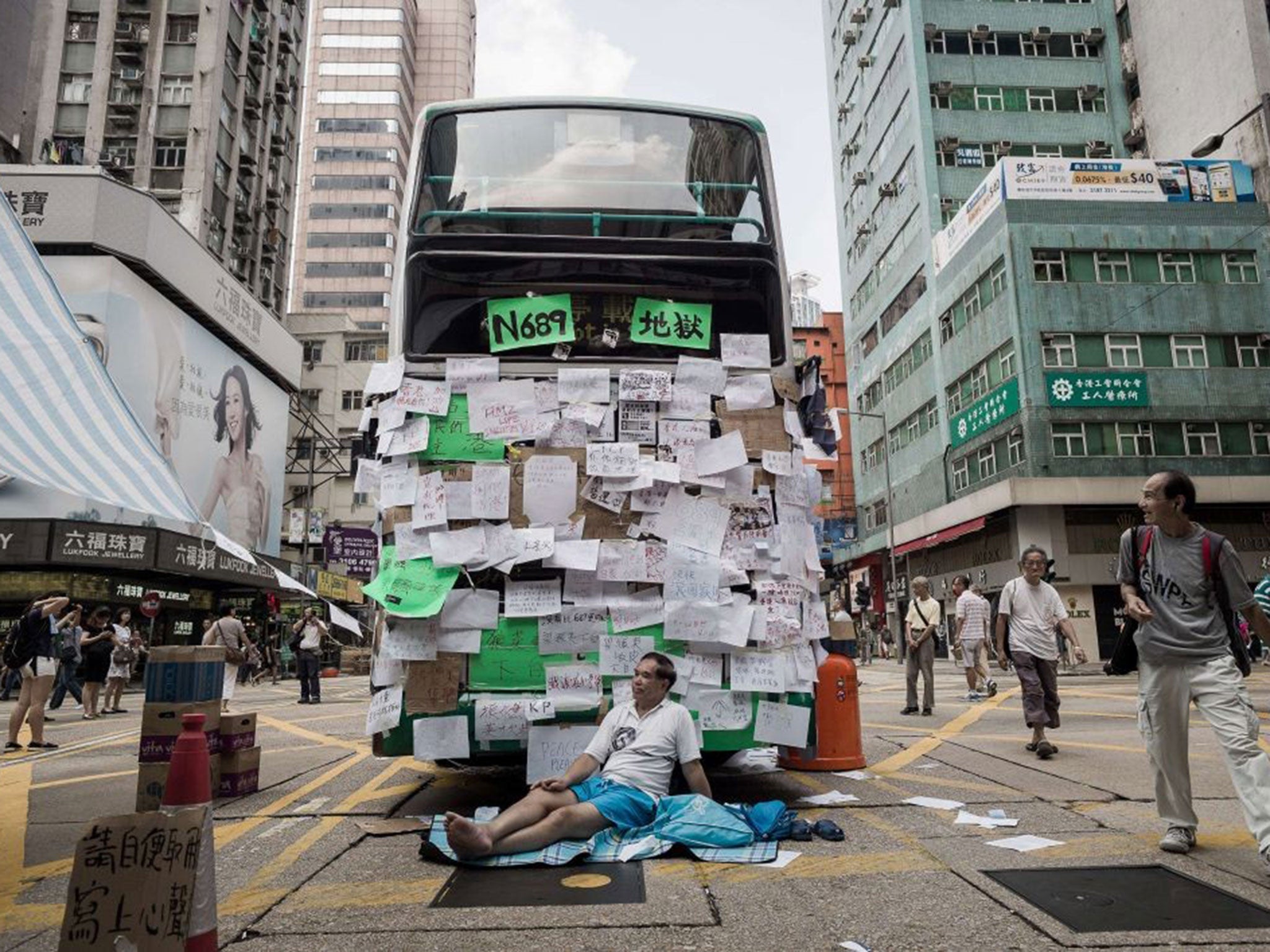 A pro-democracy demonstrator guards a bus placarded with messages of support in Hong Kong