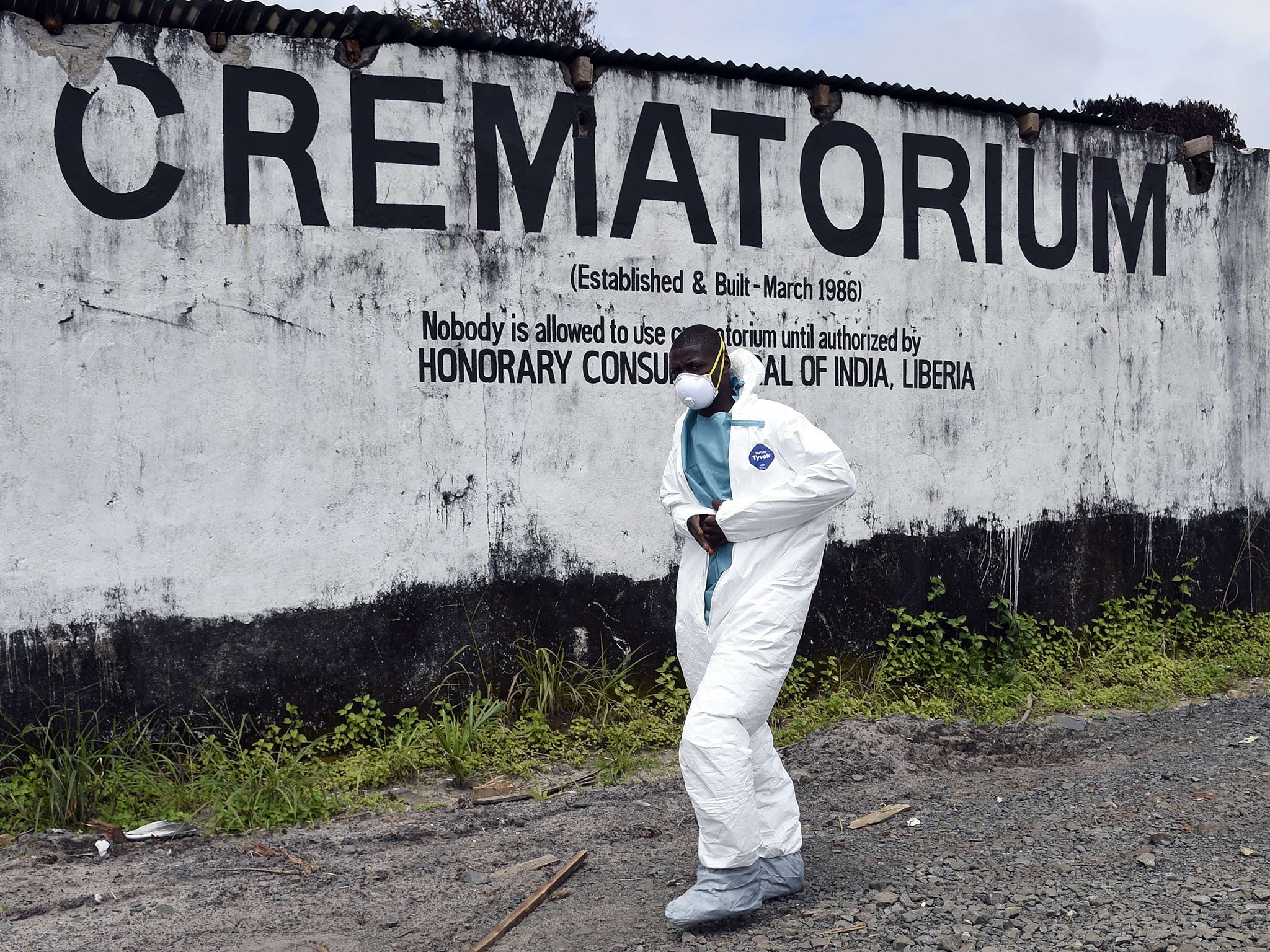 A medical staff member wearing a protective suit walks past the crematorium where victims of Ebola are burned in Monrovia