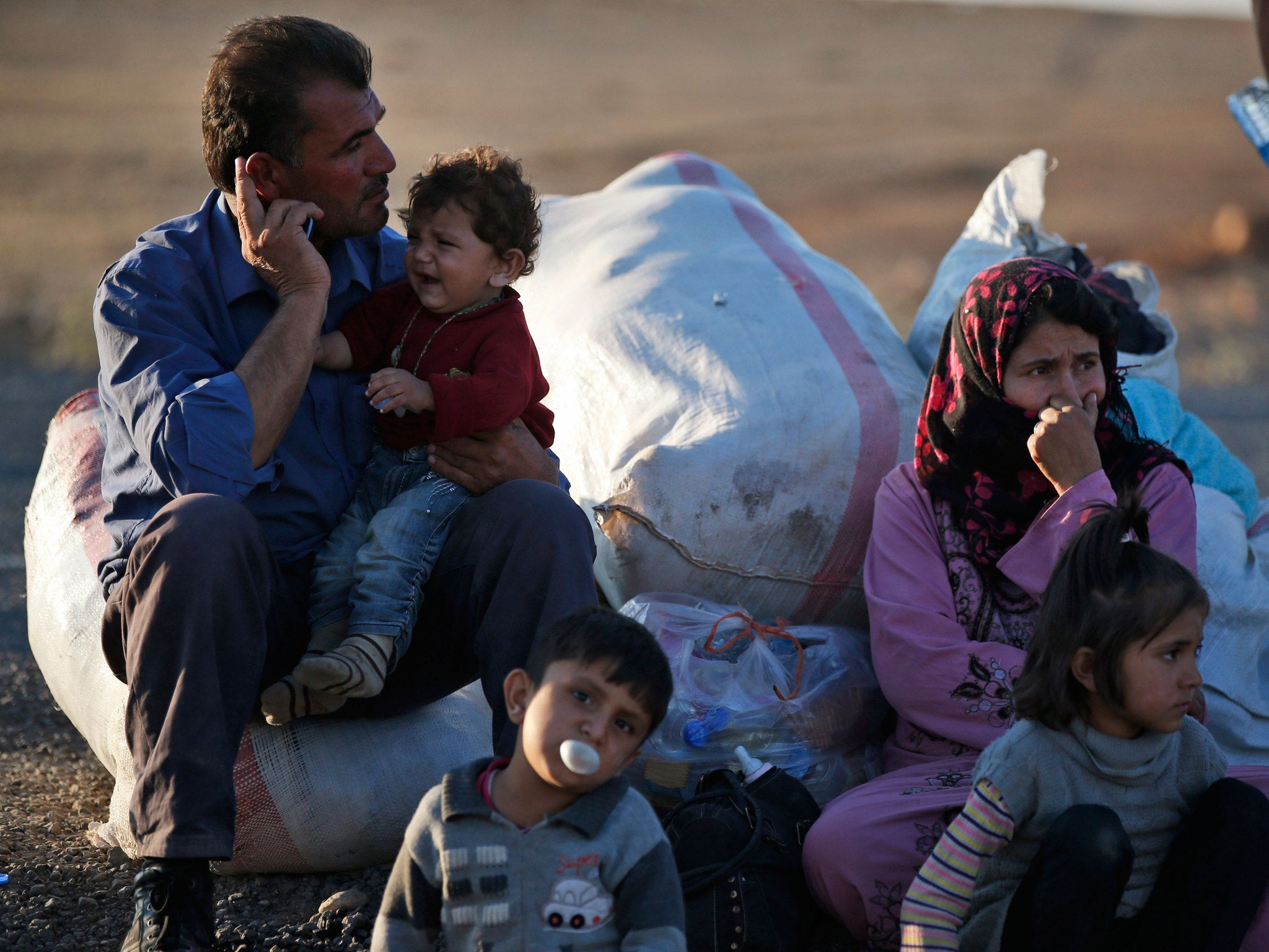 Kurdish refugees wait by the side of the road near Suruc, Turkey, after their arrival from Kobani, as fighting intensified between Syrian Kurds and Isis