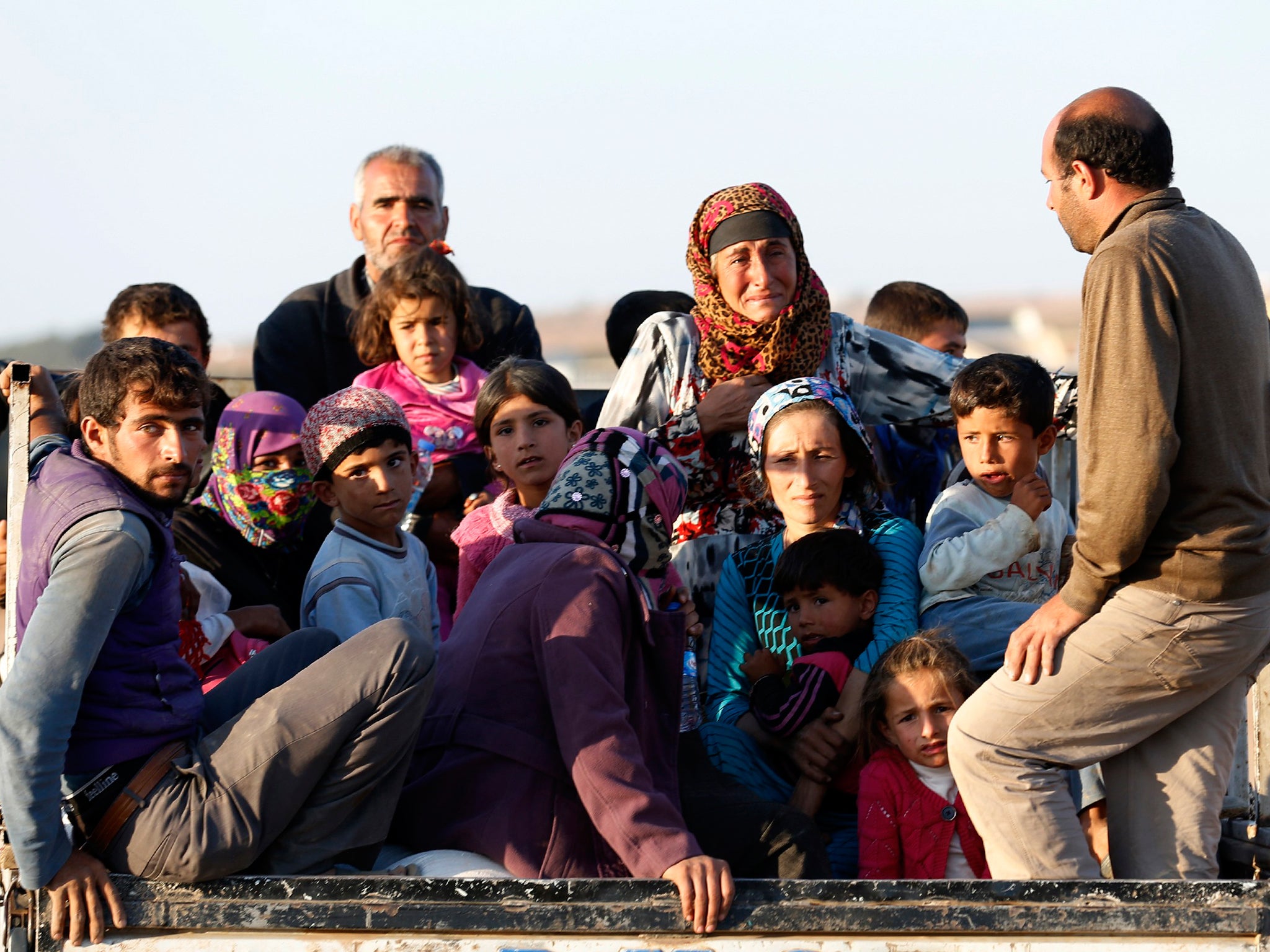 Newly arrived Syrian Kurdish refugees stand at the back of a truck after crossing into Turkey from the Syrian border town Kobani, near the southeastern Turkish town of Suruc in Sanliurfa province