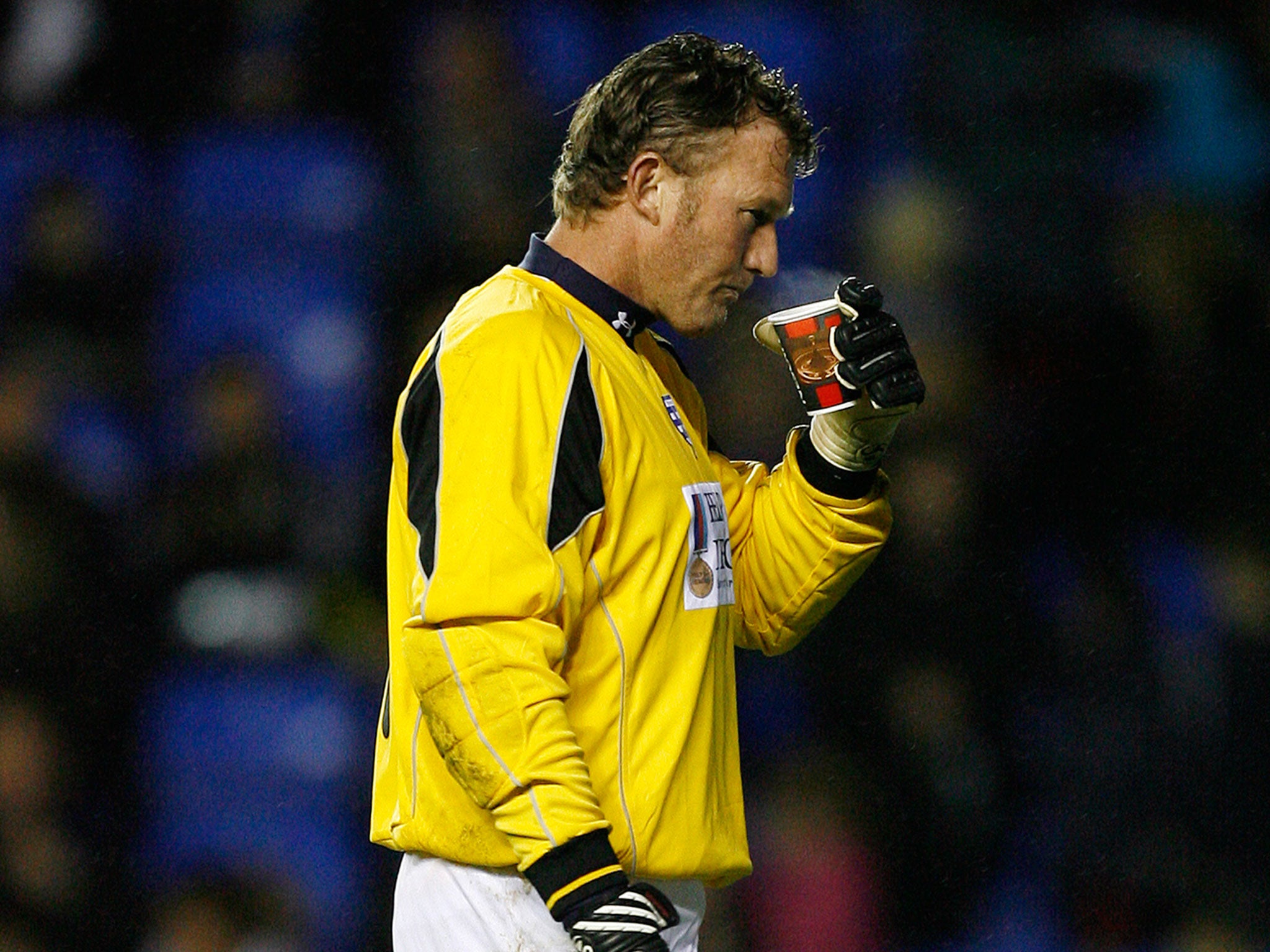 Beasant walks onto the pitch with a cup of coffee during a charity match in 2009