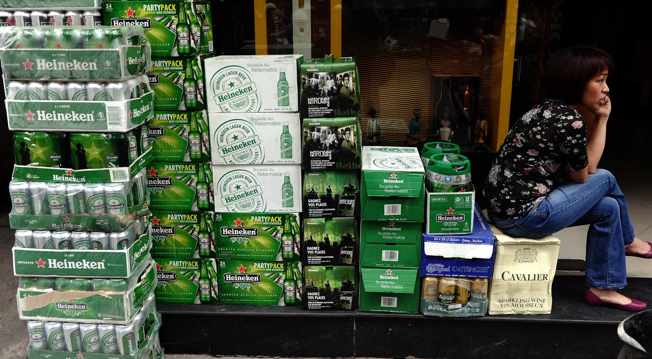 A shopkeeper sits next to boxes of imported beer in Vietnam