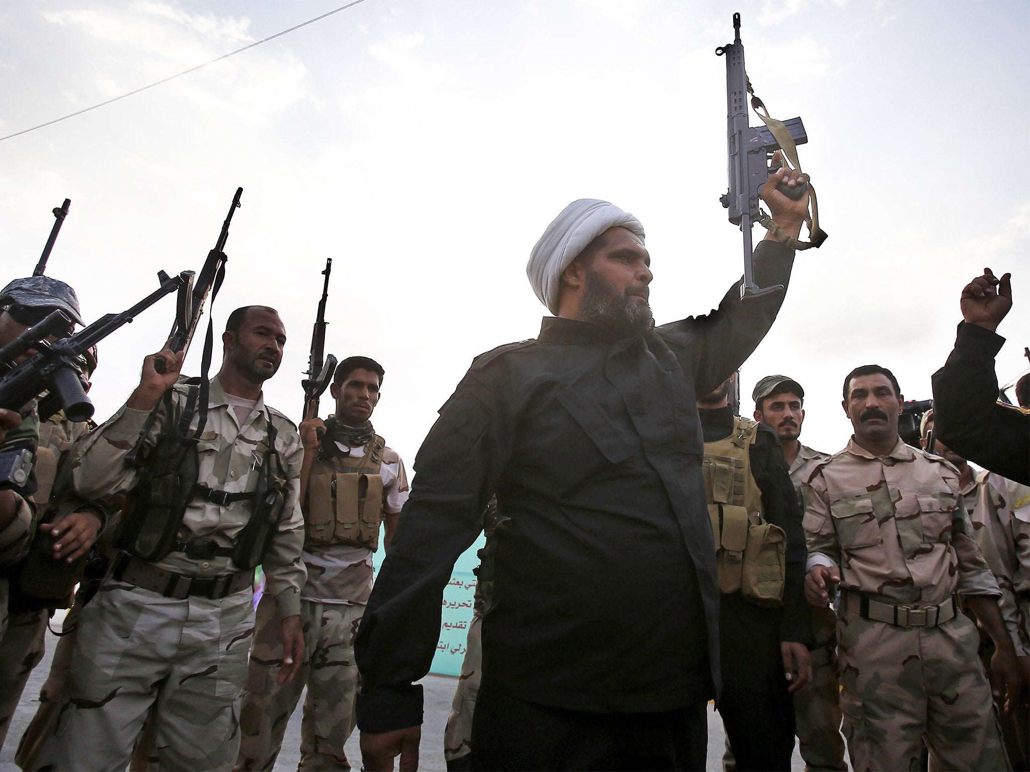 Shia militia fighters brandish their weapons in the shrine city of Karbala before joining the fight against Isis (Getty)