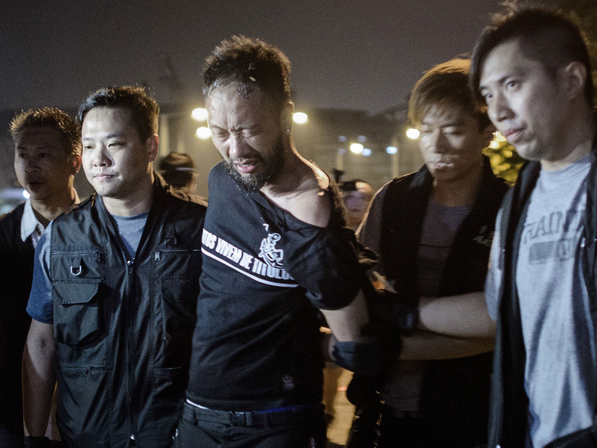 Civic Party member Ken Tsang shown as he is taken away by policemen and before an alleged beating captured on local TV cameras