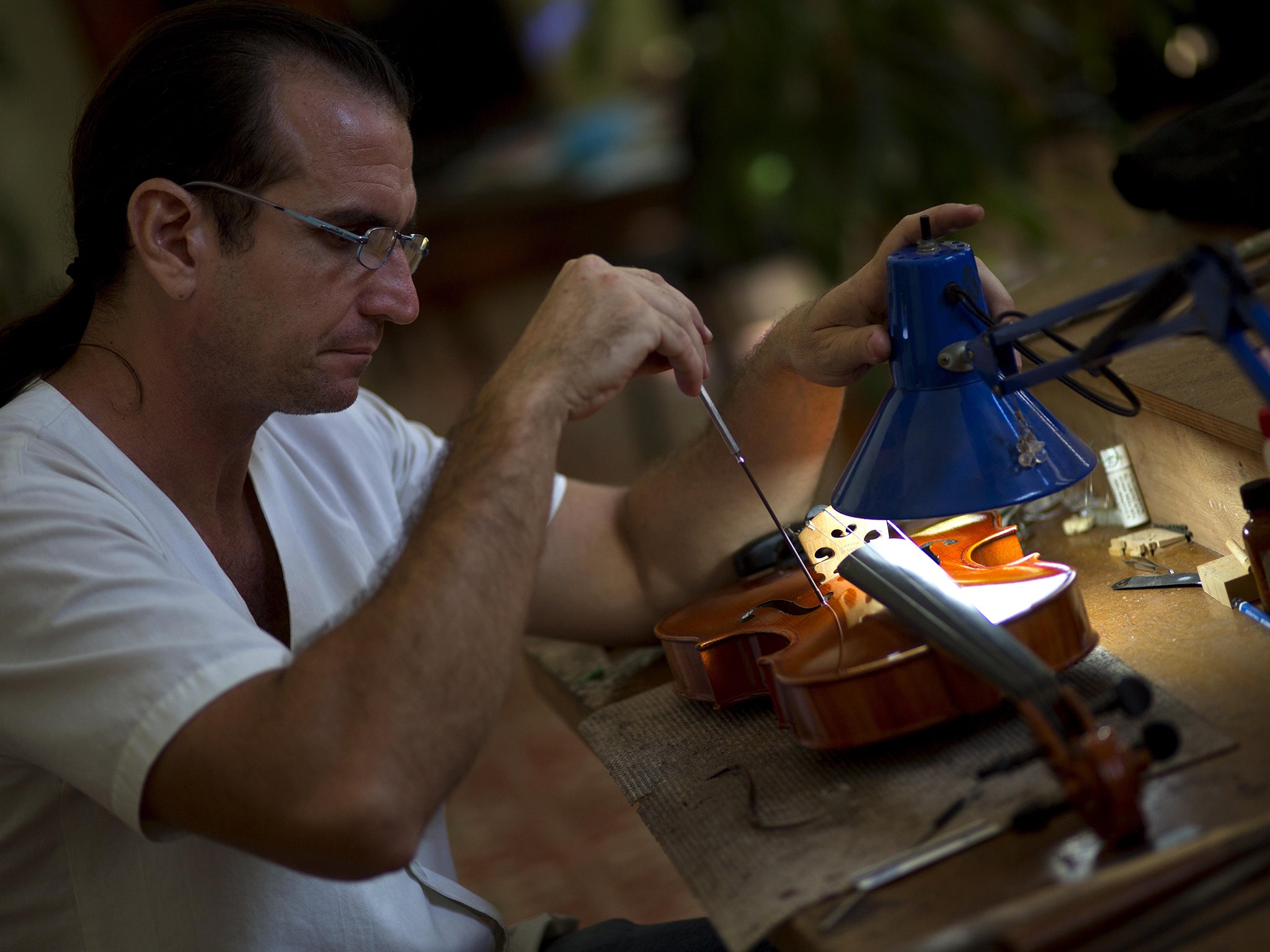 Andres Martinez repairs a viola at his workshop in Havana