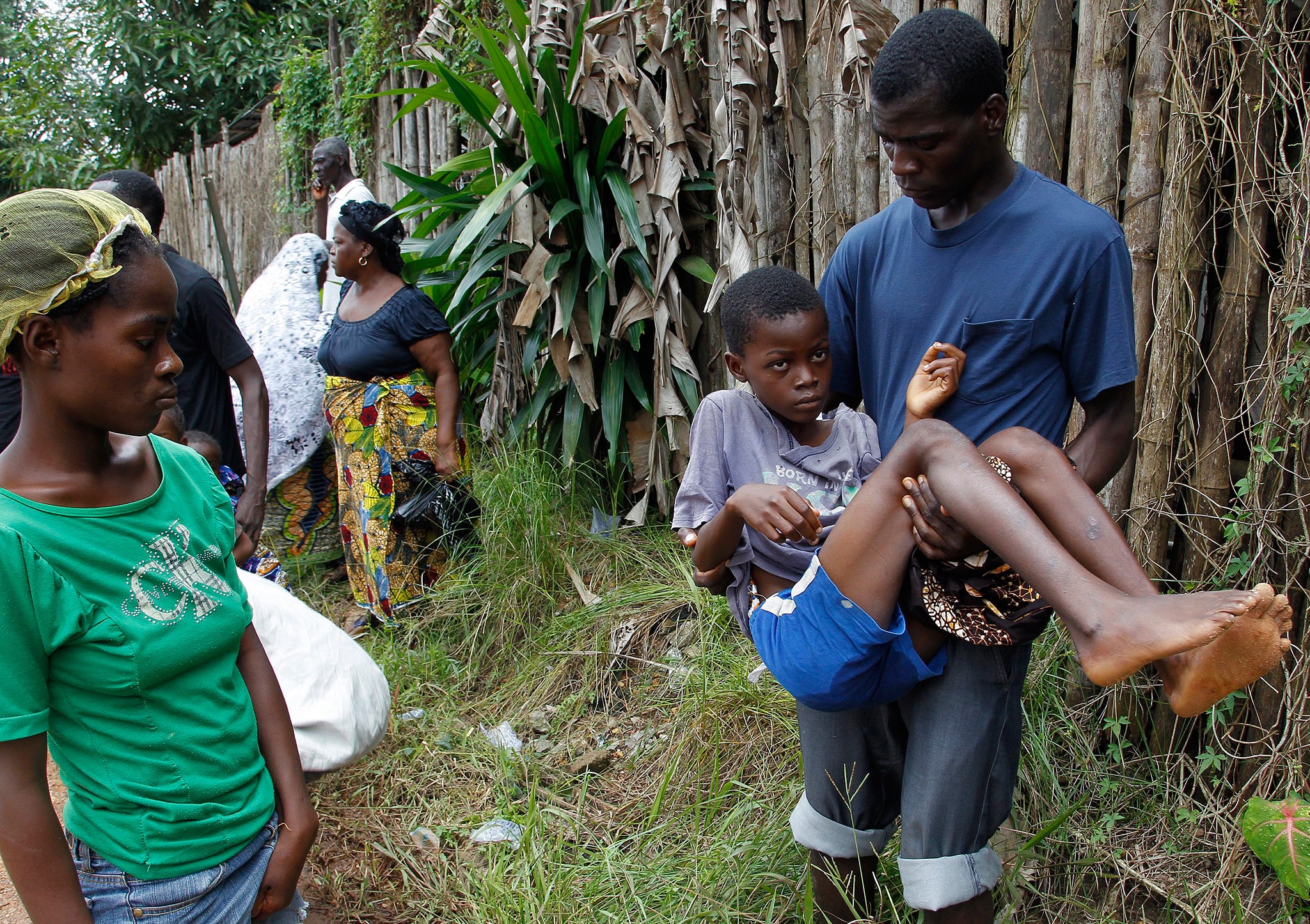 A Liberian man carries his sick brother suspected of having Ebola after being delayed admission to the Island Clinic Ebola Treatment Unit due to a lack of beds at the clinic on the outskirts of Monrovia, Liberia