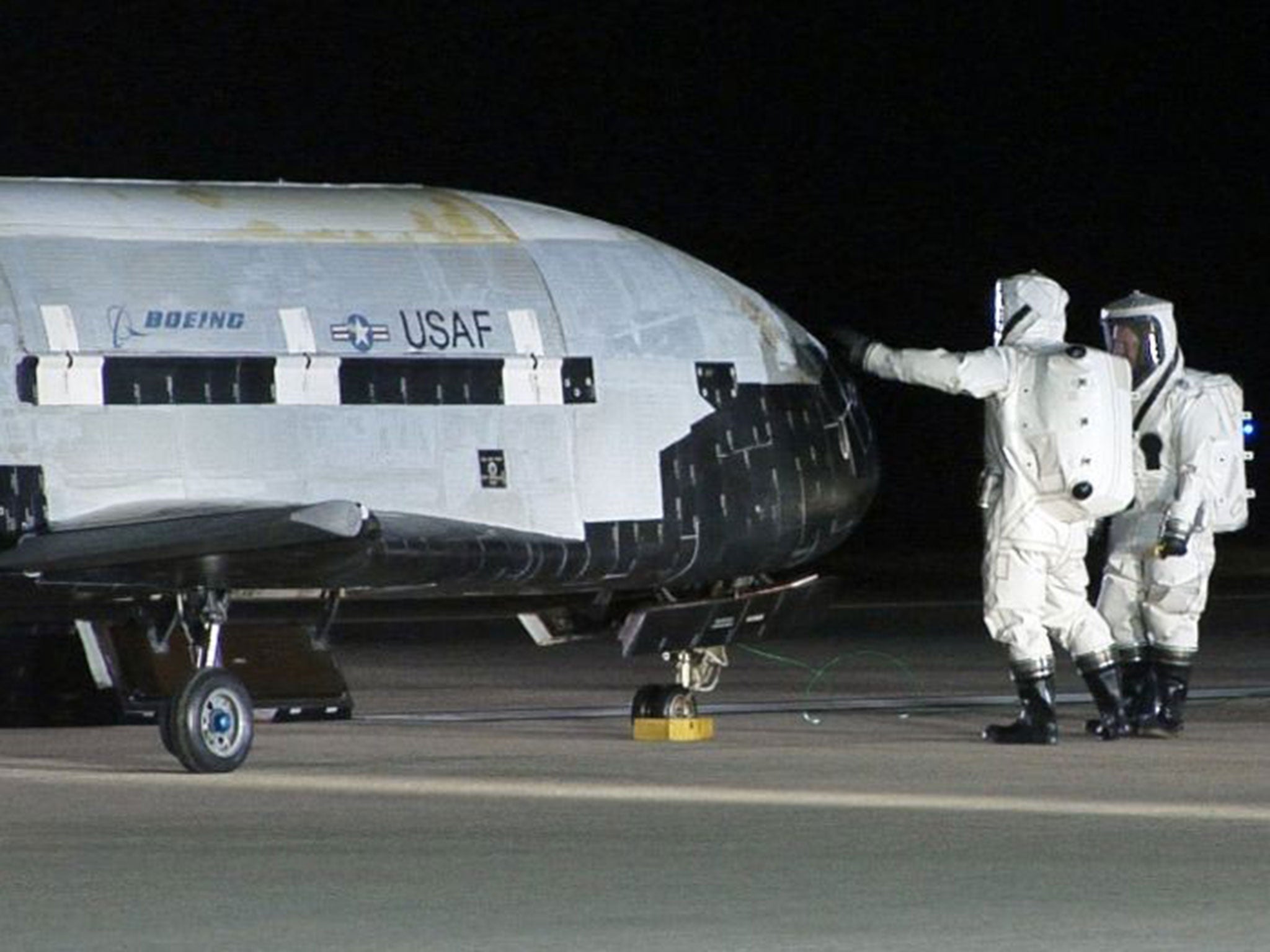 Technicians examining the X-37B unmanned spaceplane shortly after landing at Vandenberg Air Force Base, Calif