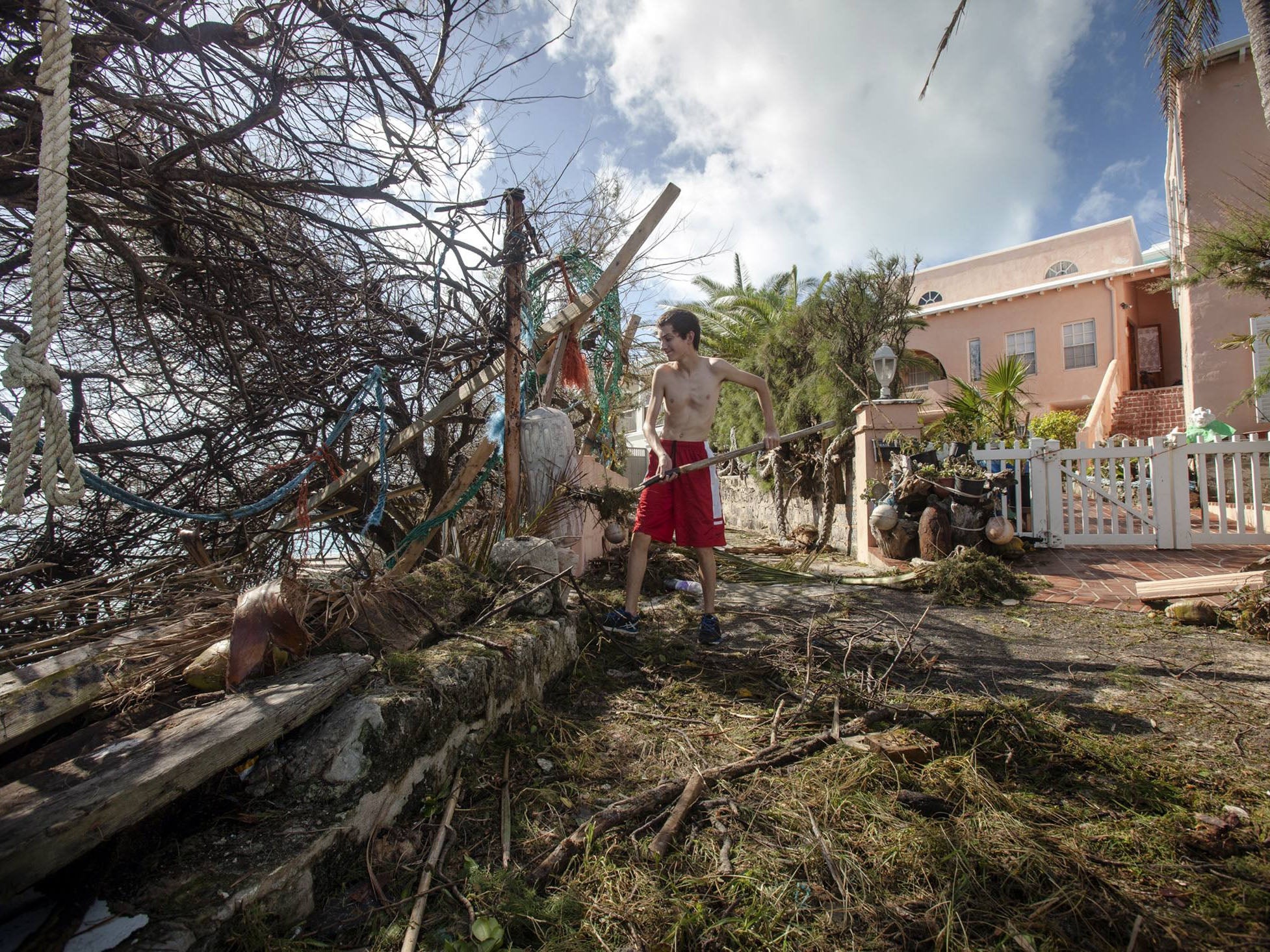 Stefano Ausenda shovels debris away from his driveway in Bermuda after Hurricane Gonzalo passed through