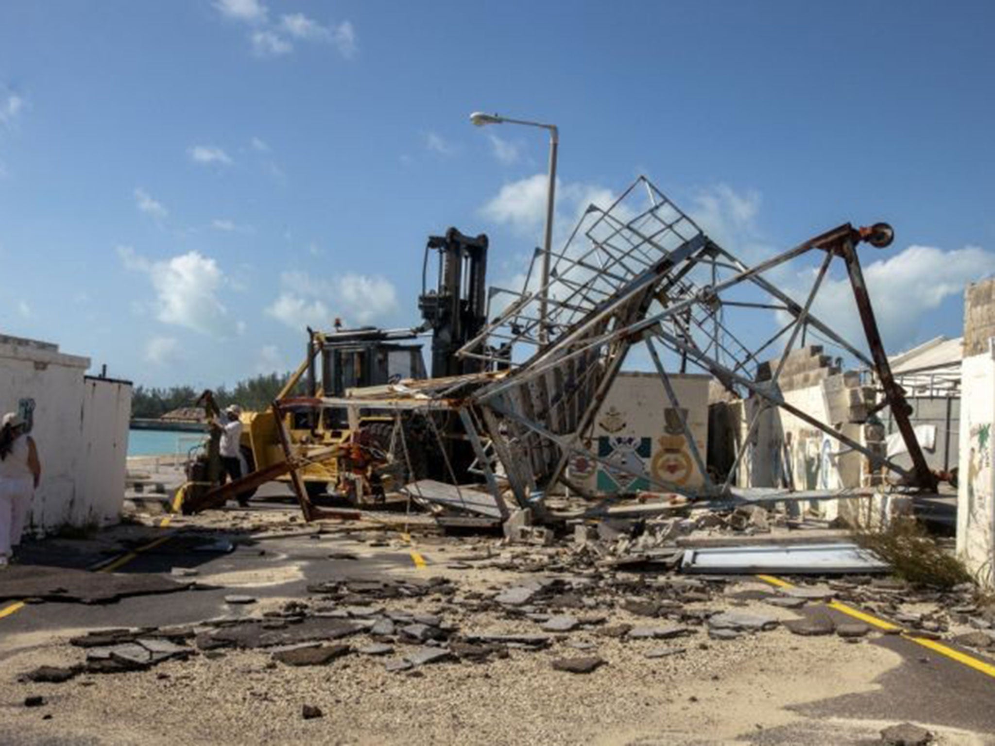 A woman walks around debris after Hurricane Gonzalo passed through the Royal Naval Dockyard, western Bermuda,