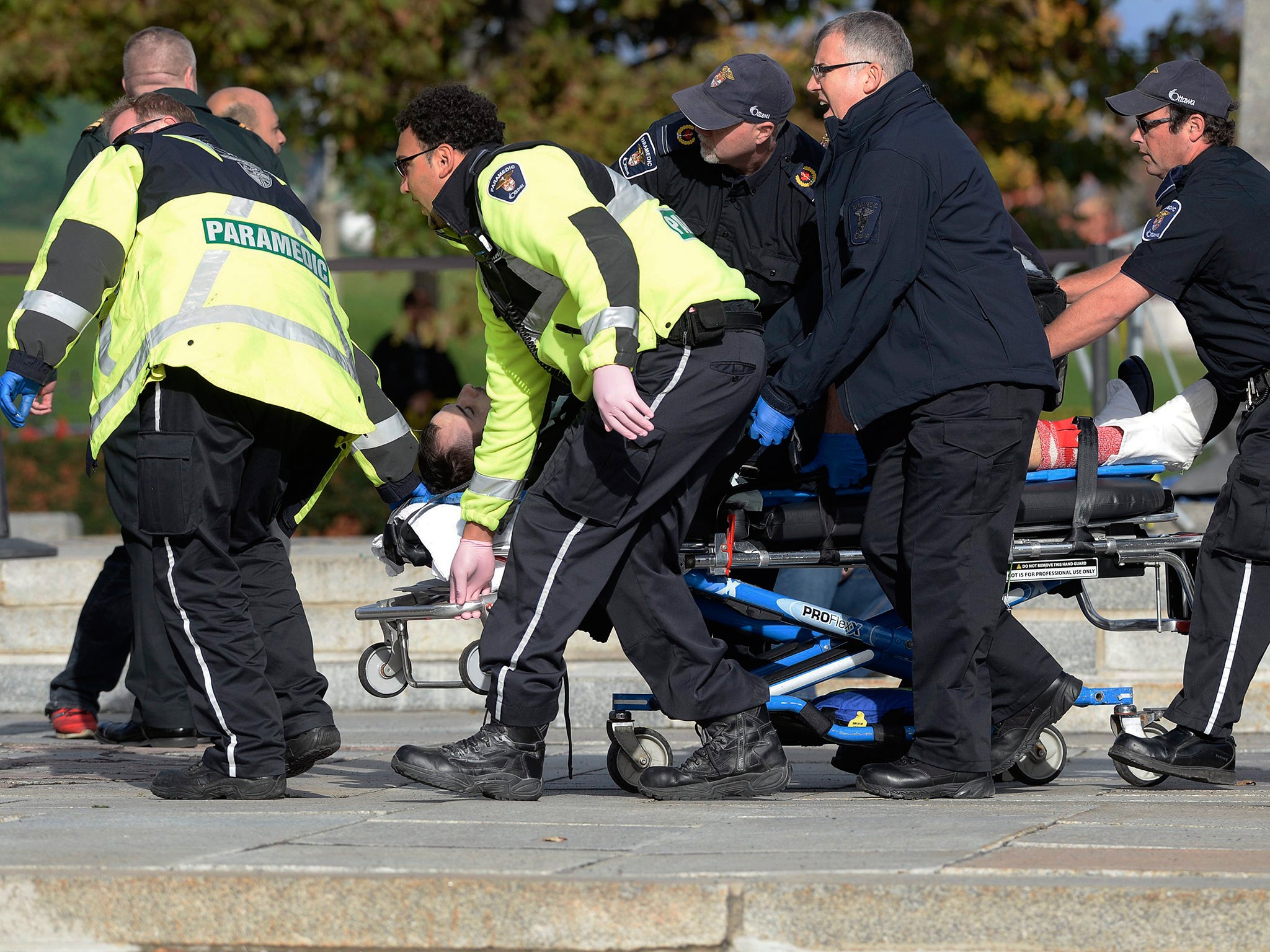 Paramedics and police pull a victim away from the Canadian War Memorial in Ottawa