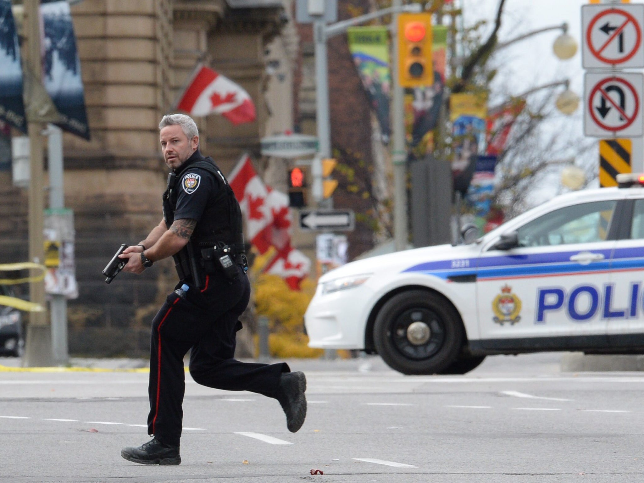An Ottawa police officer runs with his weapon drawn outside Parliament Hill in Ottawa