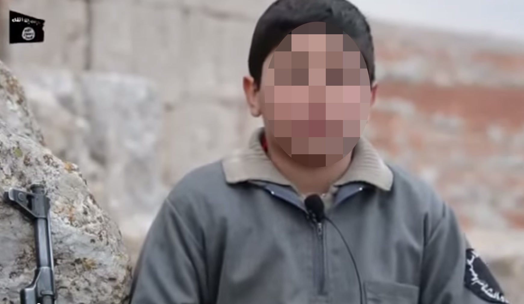 Young boys are interviewed about the beliefs fostered at the school - while sitting holding rifles