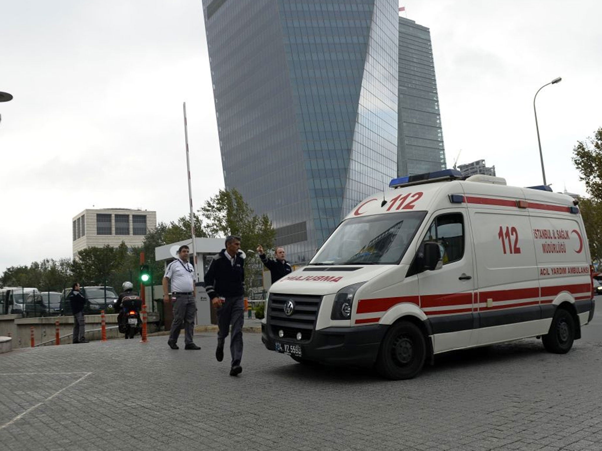 Security guards speak with the personnel of an ambulance arrived at the entrance of a building, unseen, where the Canadian consulate is located in Istanbul, Turkey