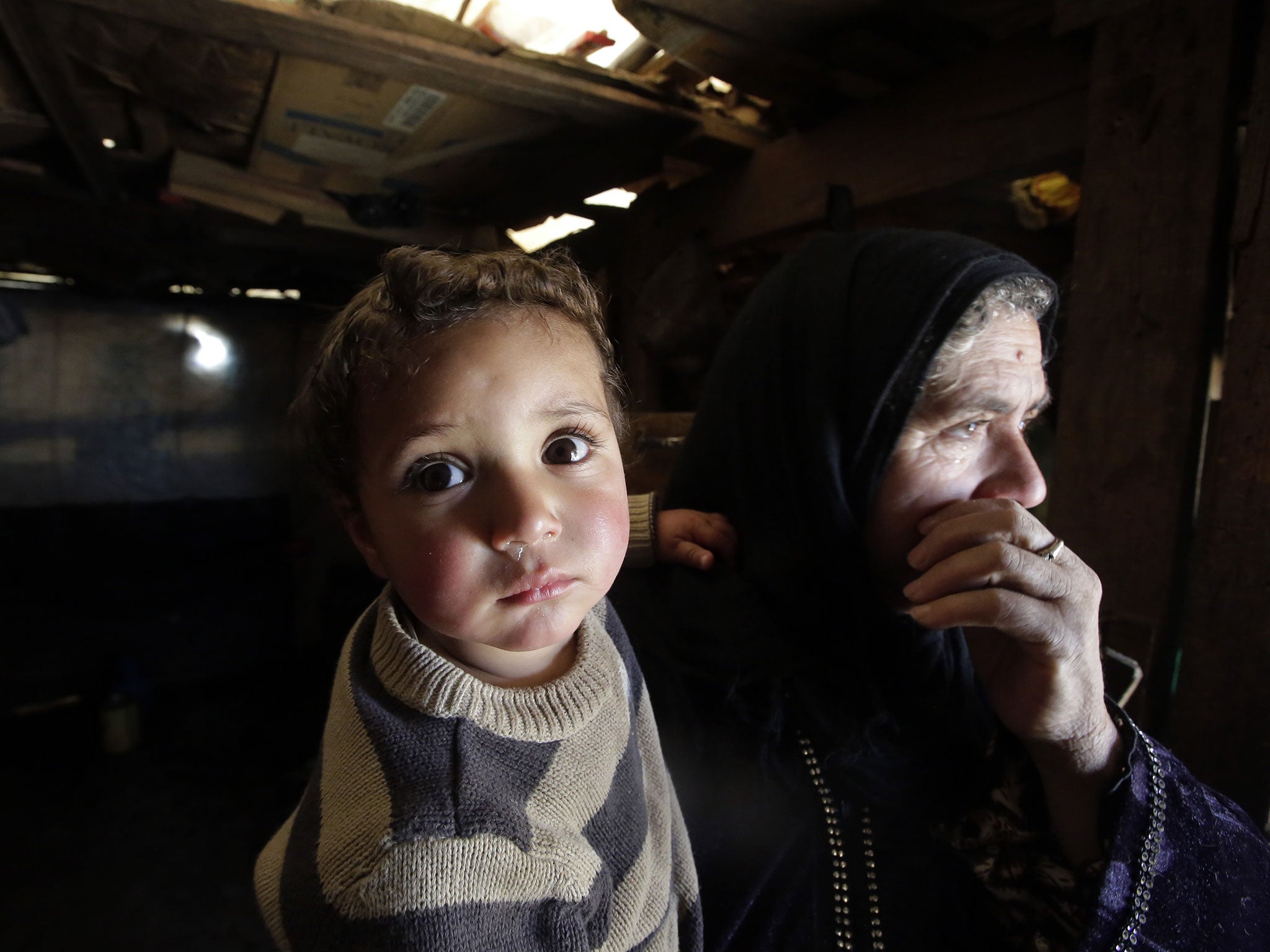 An elderly Syrian woman carries her two-year-old grandson Mohammed who, according to her, was born on the day of the outbreak of the Syrian revolution