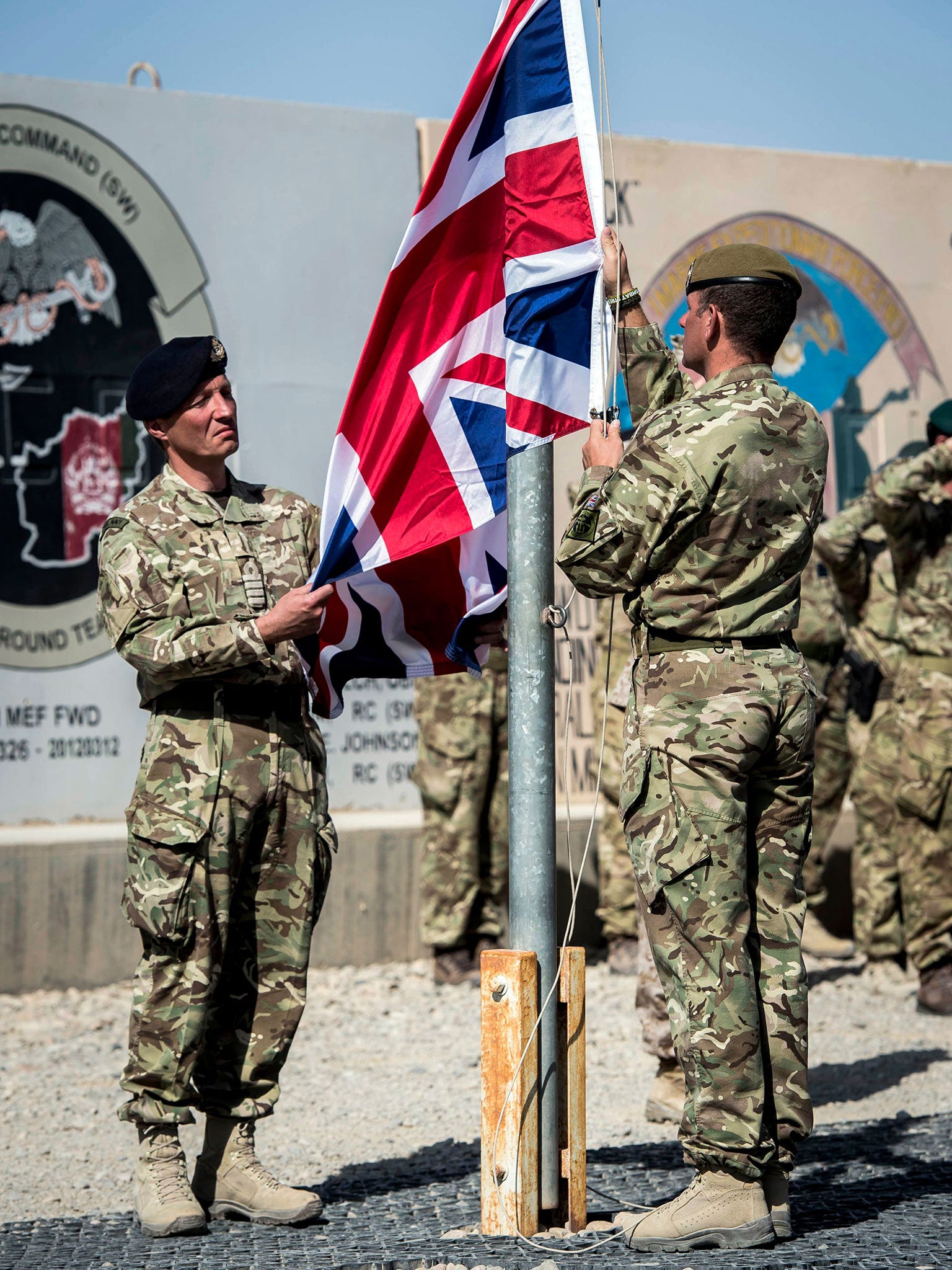 The last Union Flag flying above Helmand Province is lowered by Captain Matthew Clark, left, and Warrant Officer John Lilley