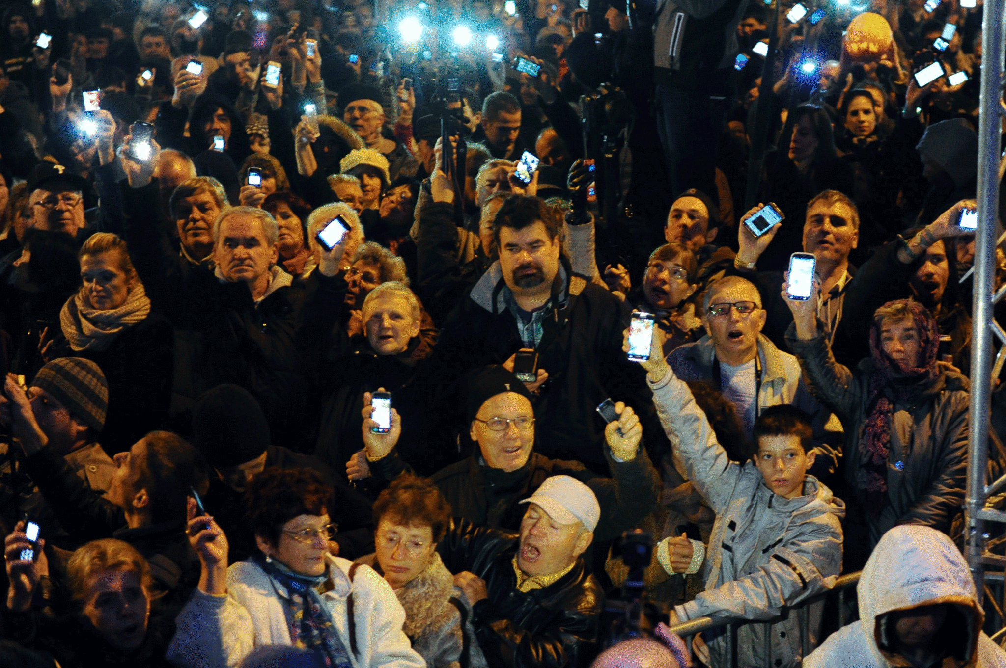 Hungarian citizens lift their mobile phones to protest against the goverment's new tax plan for the introduction of the internet tax next year in Budapest