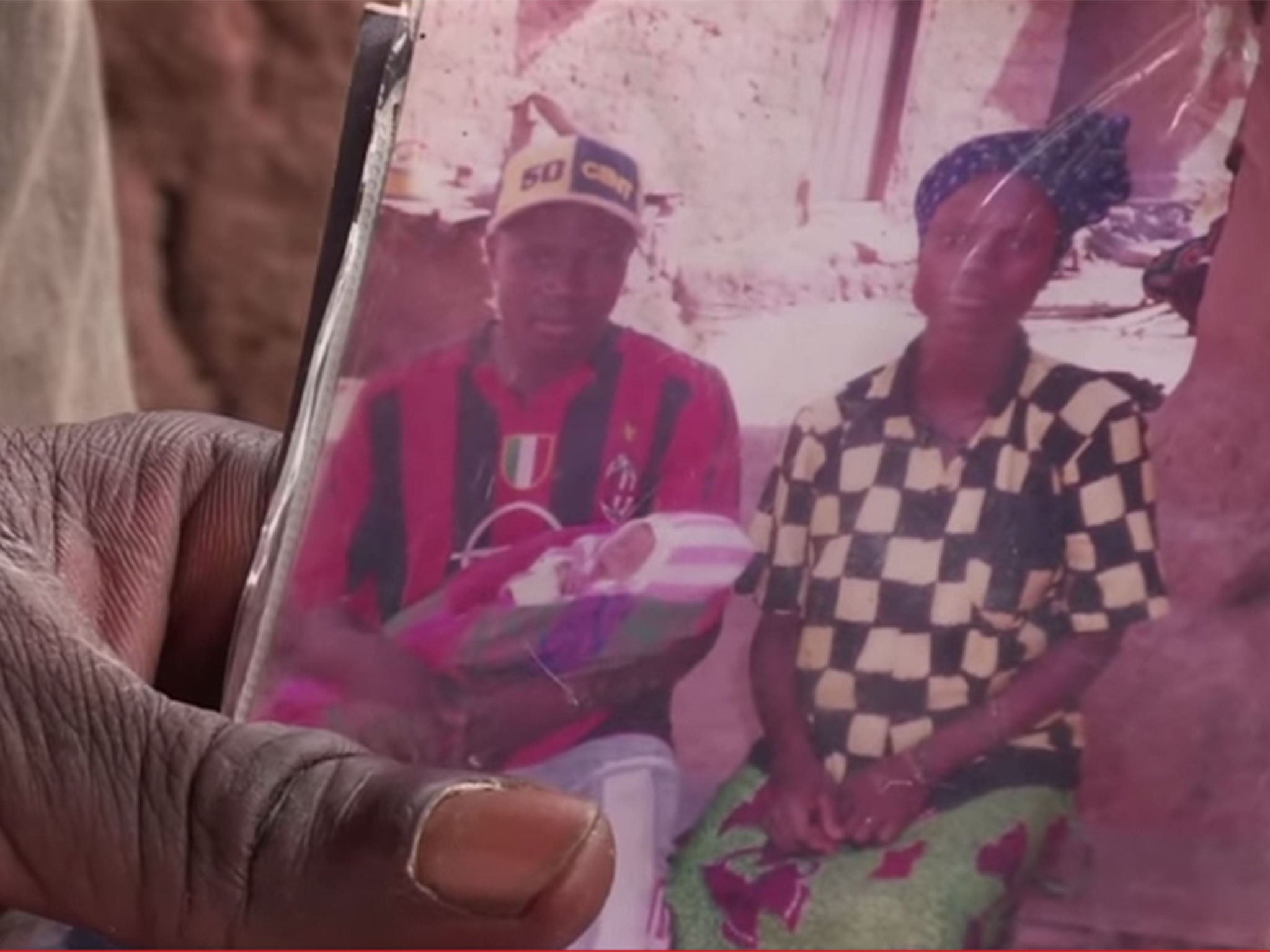 Etienne Ouamouno sits holding baby Emile, who has been identified as the first traceable patient of the current Ebola outbreak