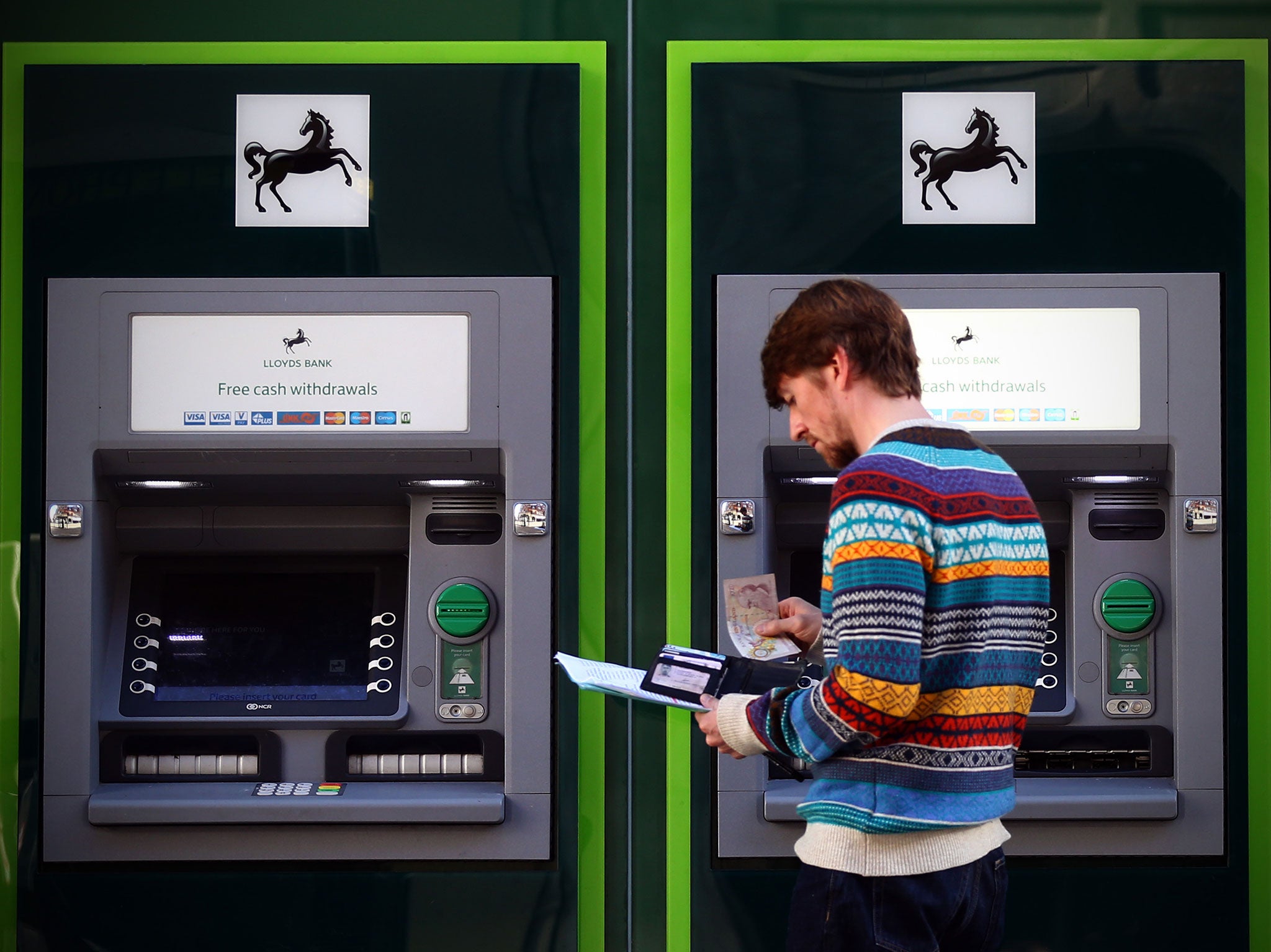 A man withdraws money from a cash machine at a branch of Lloyds Bank on October 28, 2014 in London, England.