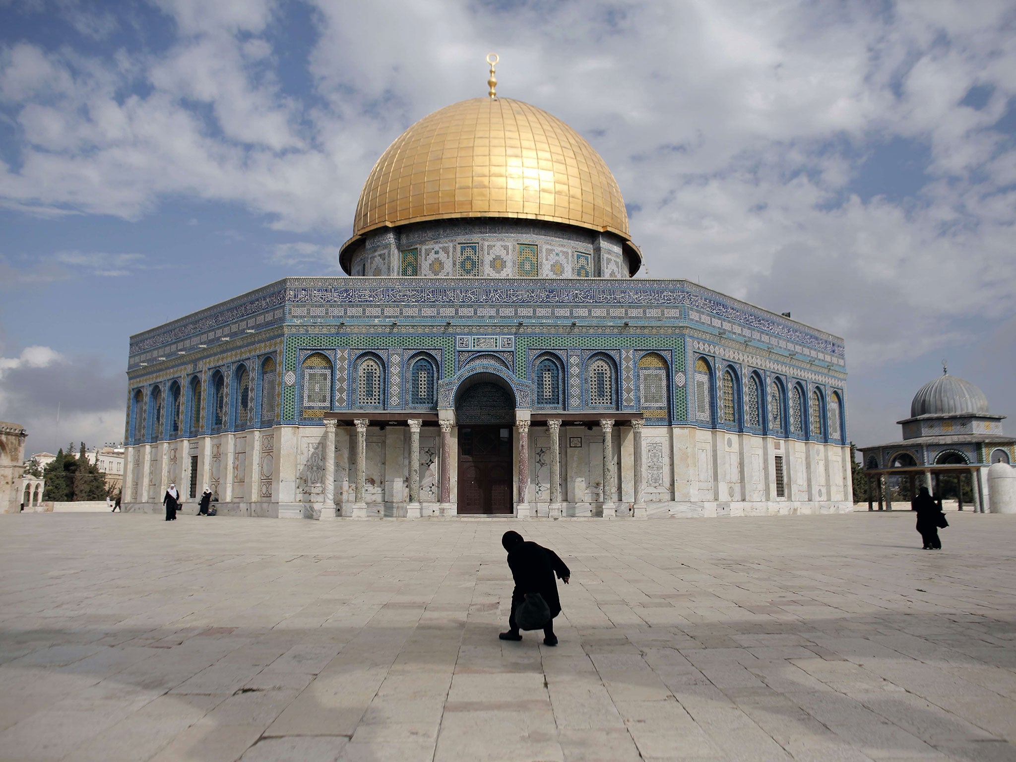 A Palestinian woman walks in front of the Dome of the Rock in the Al-Aqsa mosque compound on October 19, 2014