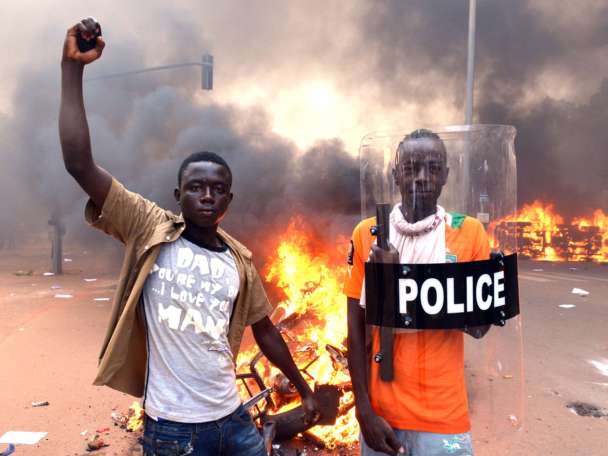 Protesters pose with a police shield outside the parliament in Ouagadougou earlier this week