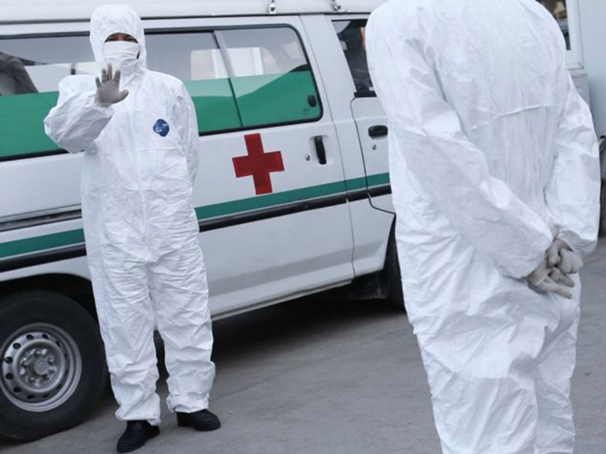 Medical personnel in protective suits standing by an ambulance, at the Sunan International Airport, in Pyongyang, North Korea.