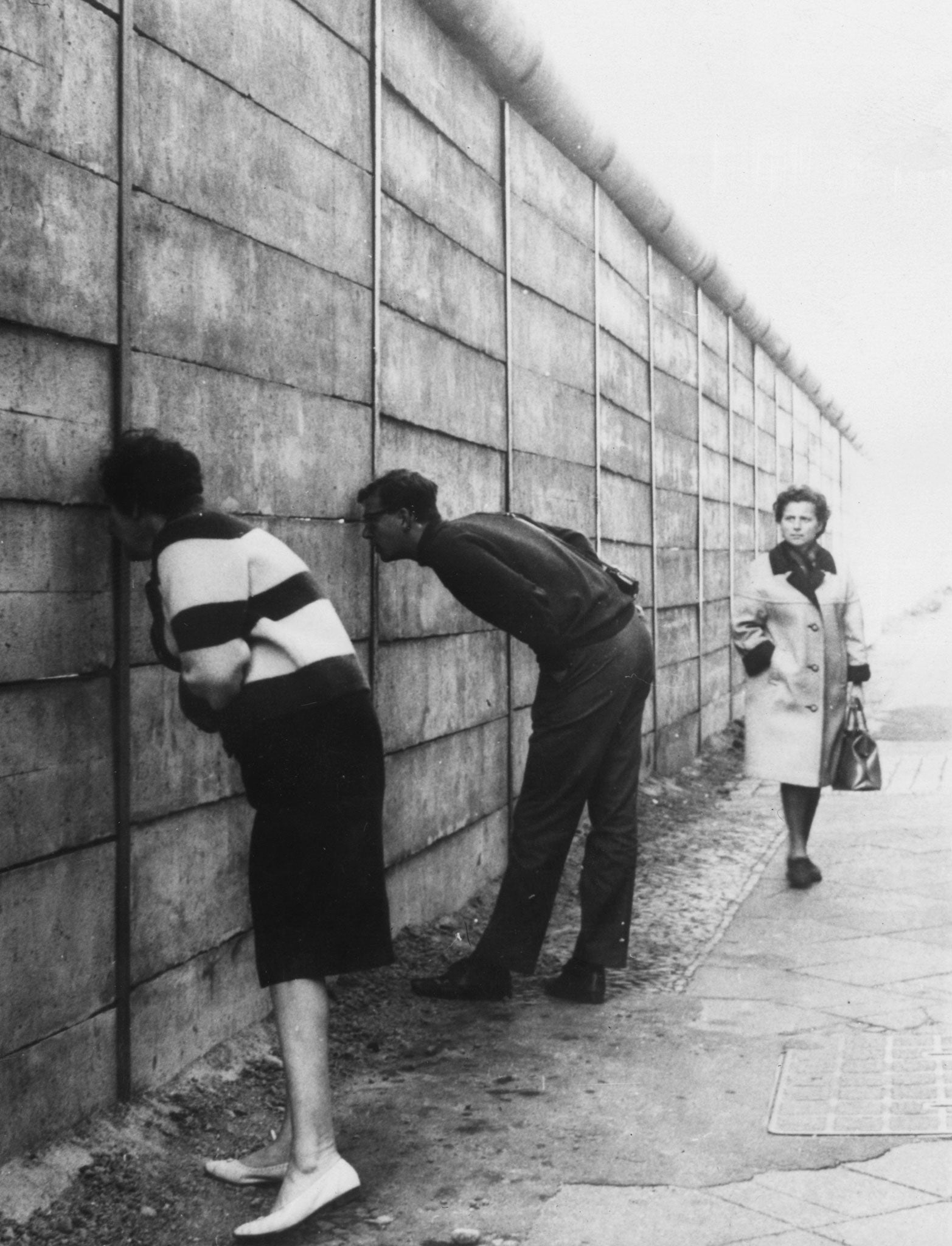 West Berliners peering through the Berlin Wall into the Eastern sector near Checkpoint Charlie, in 1966 (Getty Images)