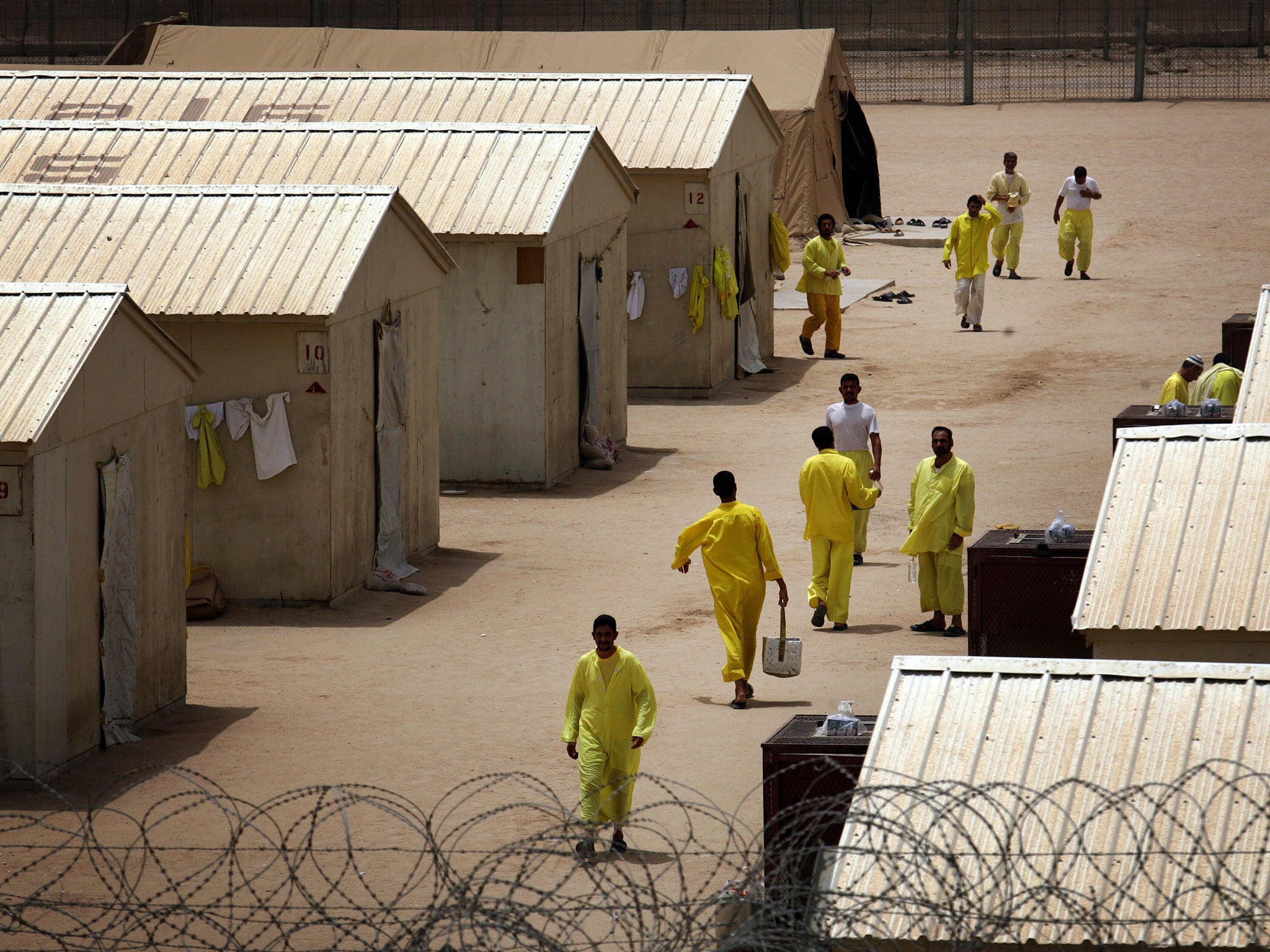 Iraqi detainees walk inside the Camp Bucca detention centre located near the Kuwait-Iraq border