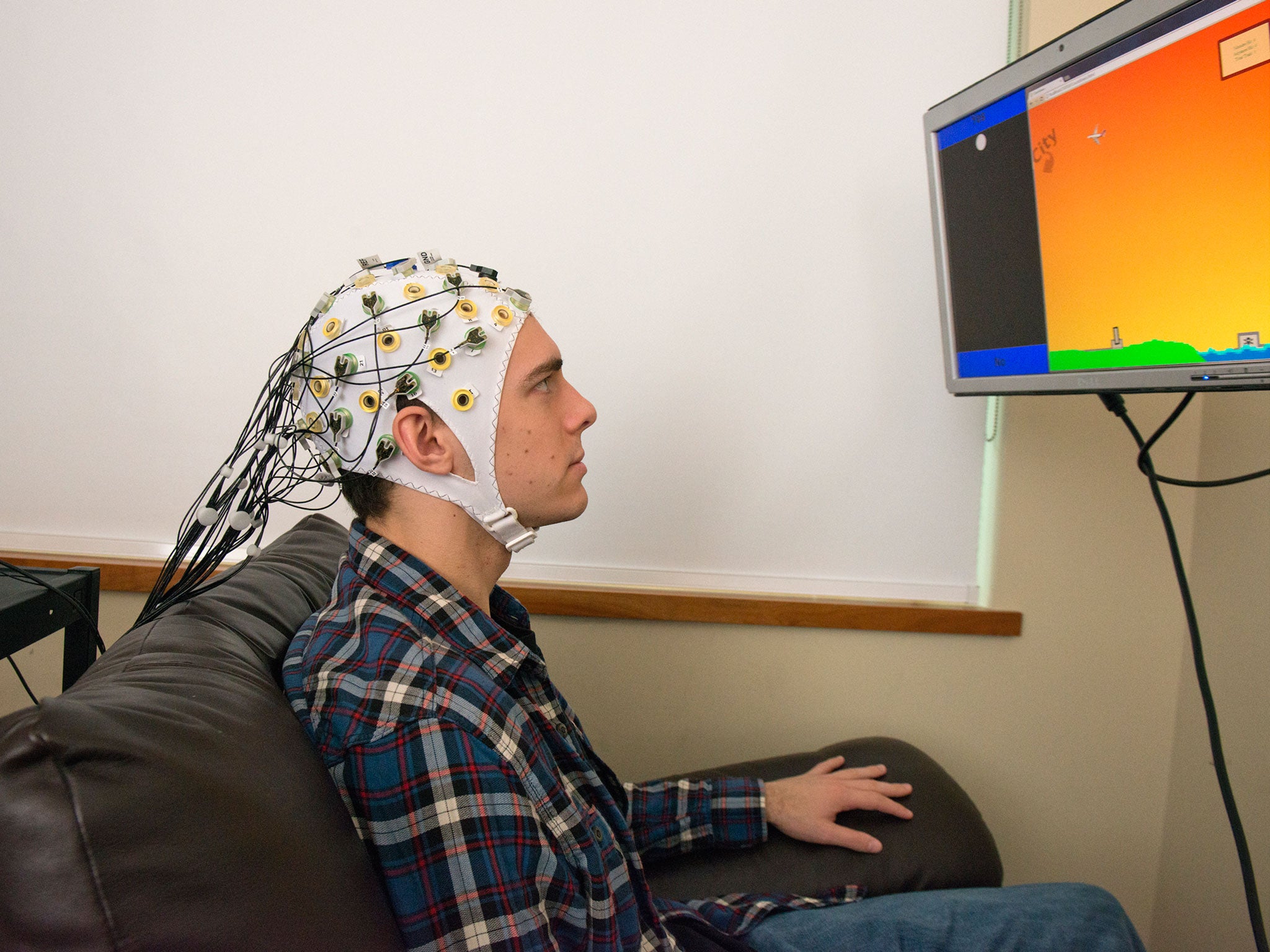 Student Darby Losey thinks about firing a cannon at various points throughout a computer game, whilst an an electroencephalography machine conveys his brain's signals directly to the brain of the receiver