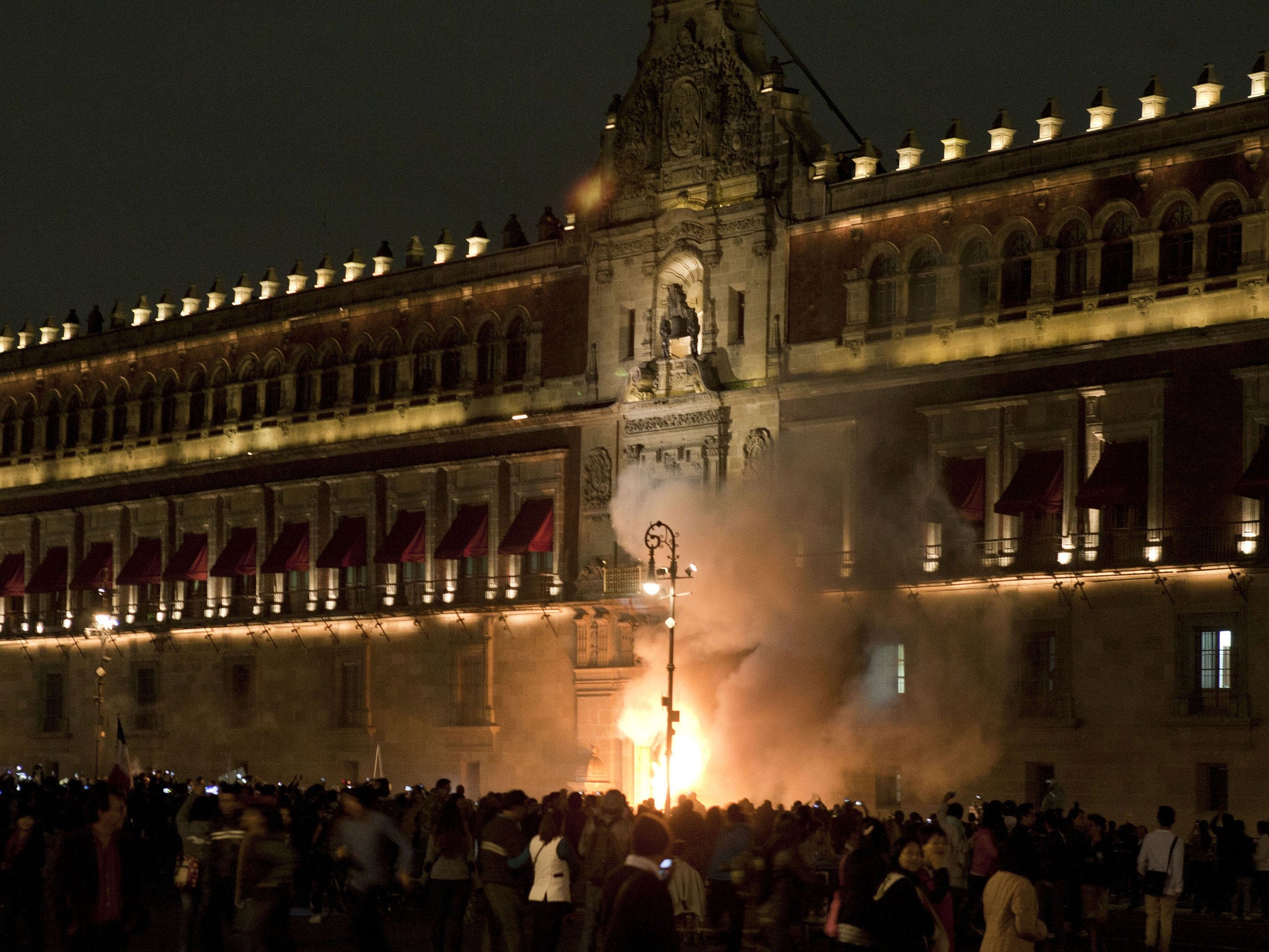 Demostrators set fire the door of the main entrance of te Mexican National Palace during a demostration in Mexico City on November 8, 2014, demanding justice from the Mexican goverment