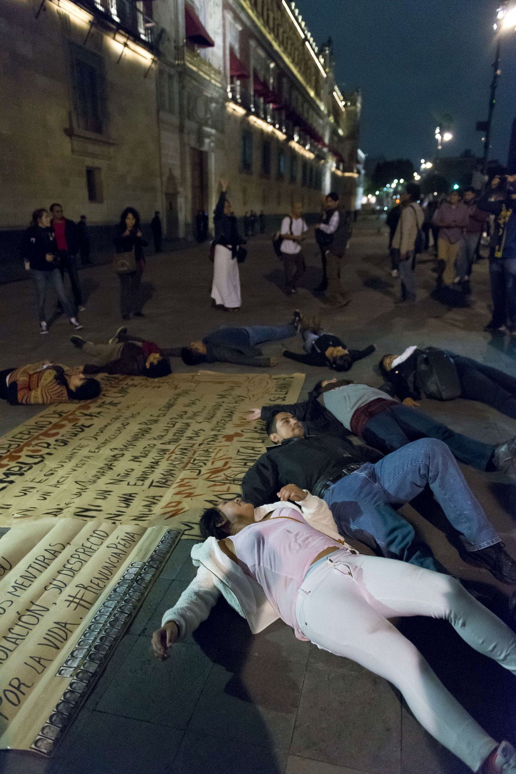 Demostrators lie down in the floor simulated the missing students in front of the main entrance of the Mexican National Palace