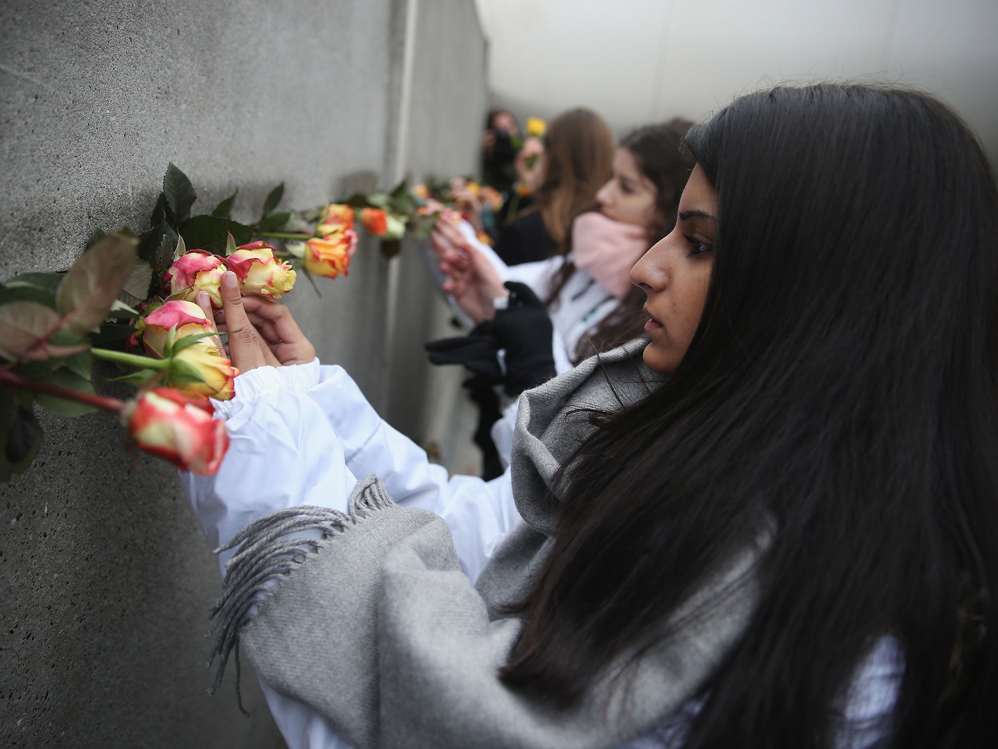 Students place flowers in the slats of remnants of the Wall at in Bernauer Strasse