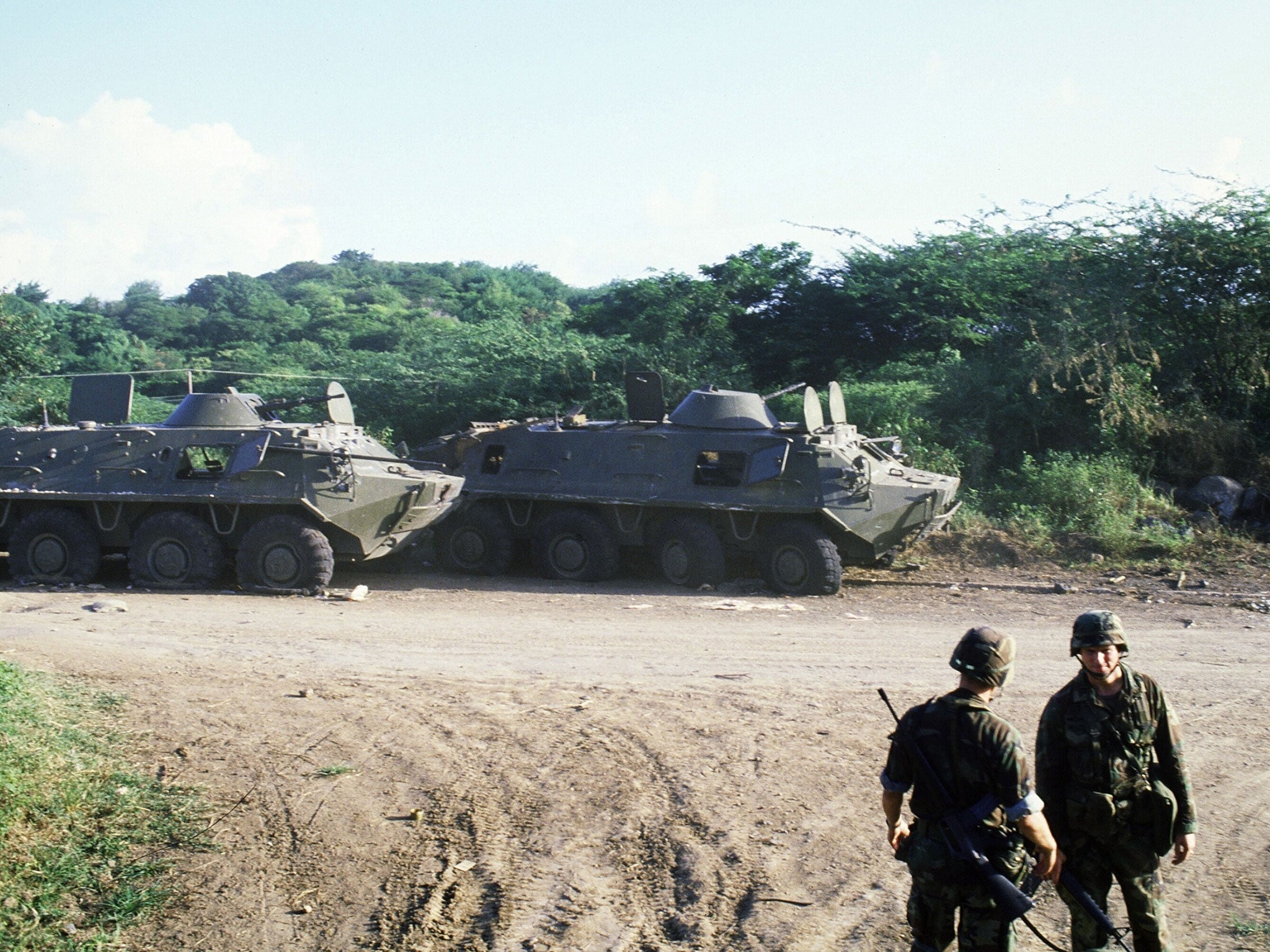 US soldiers stand next two armoured personnel vehicles as they patrol near St George's, the capital of the Grenada, three days after the invasion