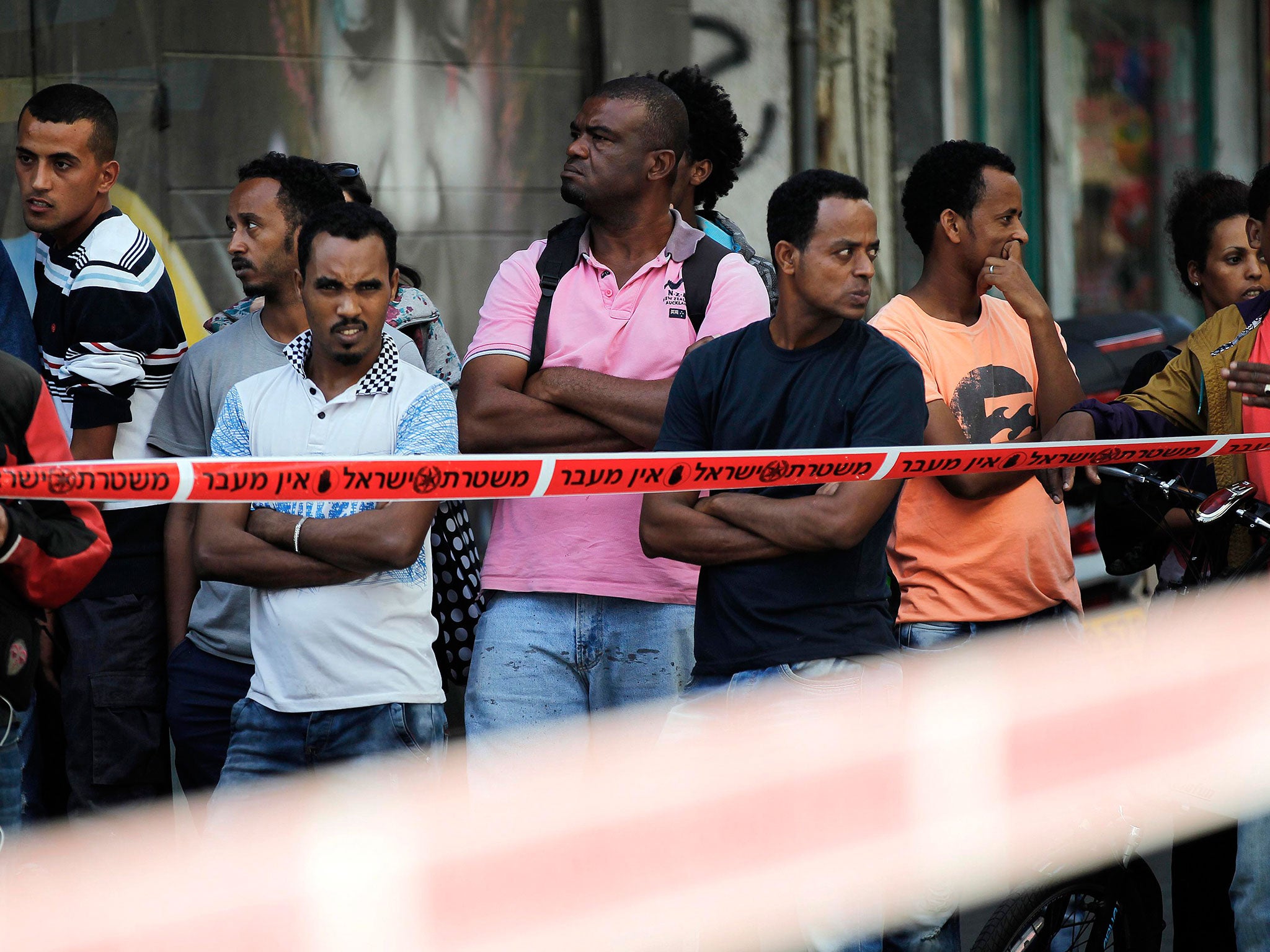 Onlookers stand at the scene of a stabbing in Tel Aviv