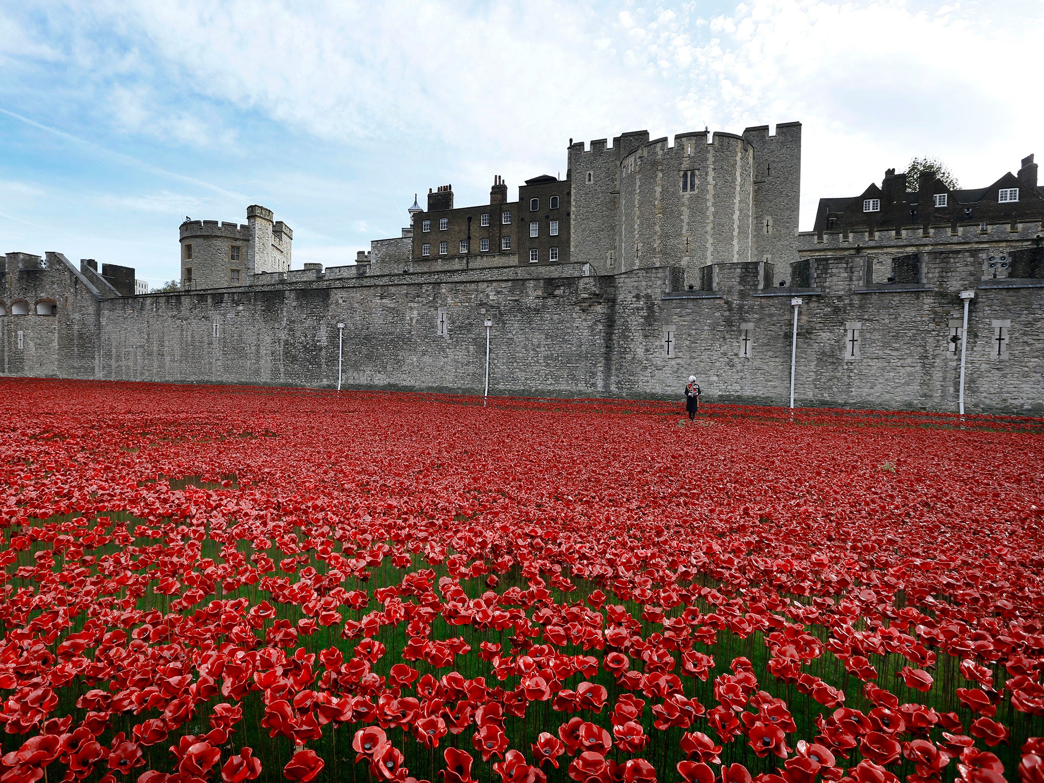 General the Lord Dannatt reads out a list of names of some of the fallen soldiers from WWI during a remembrance day ceremony by the near completed ceramic poppy art installation by artist Paul Cummins entitled 'Blood Swept Lands and Seas of Red' in the dry moat of the Tower of London, 2014