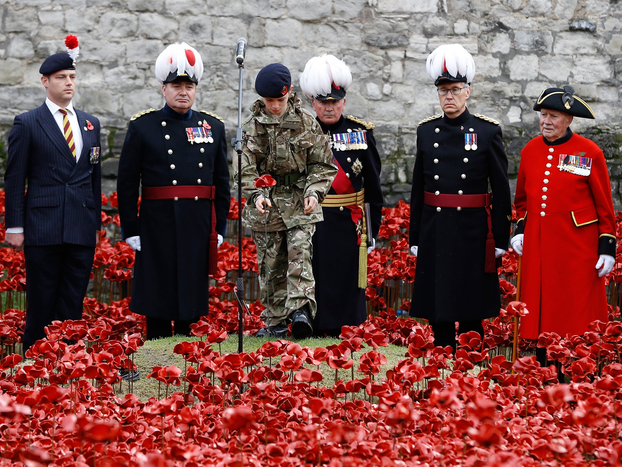 Cadet Harry Alexander Hayes plants the last poppy during a remembrance day ceremony into the ceramic poppy art installation by artist Paul Cummins entitled 'Blood Swept Lands and Seas of Red' in the dry moat of the Tower of London