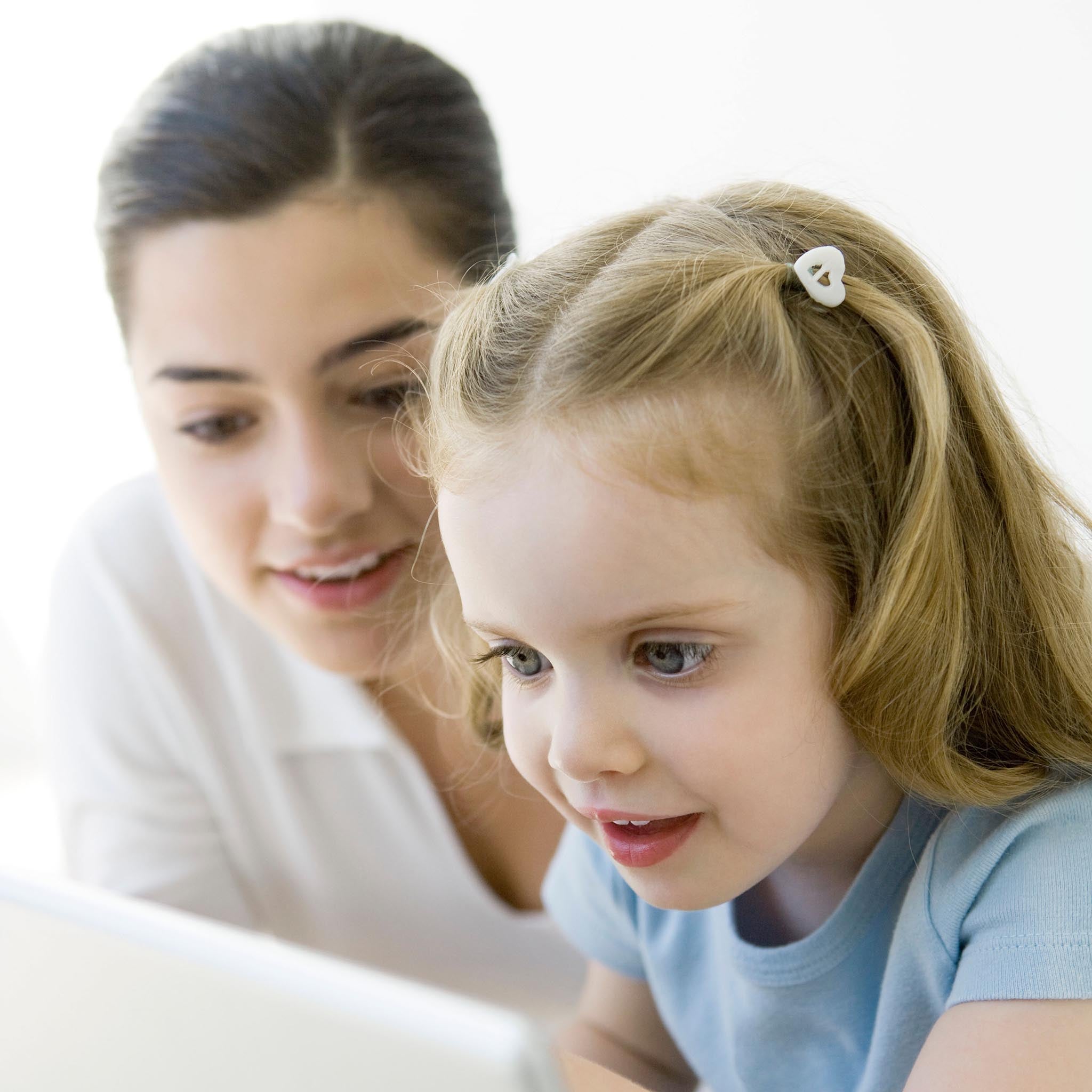 Mother and young daughter looking at laptop computer together