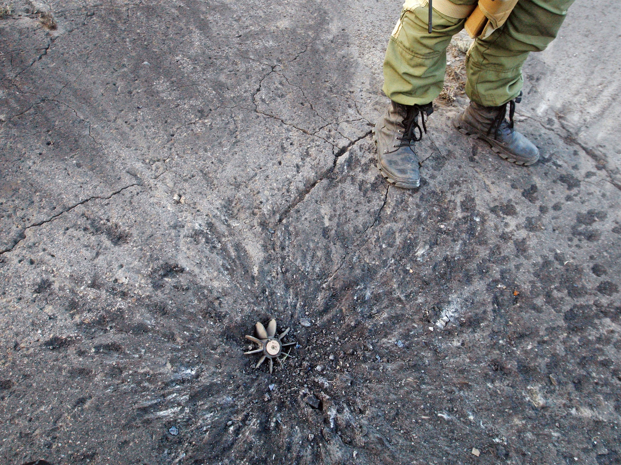 A pro-Ukrainian fighter stands next to fragment of mortar shell after shelling in Schastya, Lugansk region (Getty)