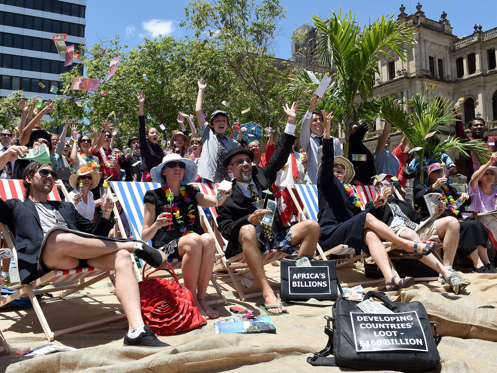 Supporters of the Micah Challenge sit on beach chairs, holding mocktails, during a protest against the upcoming G20 summit