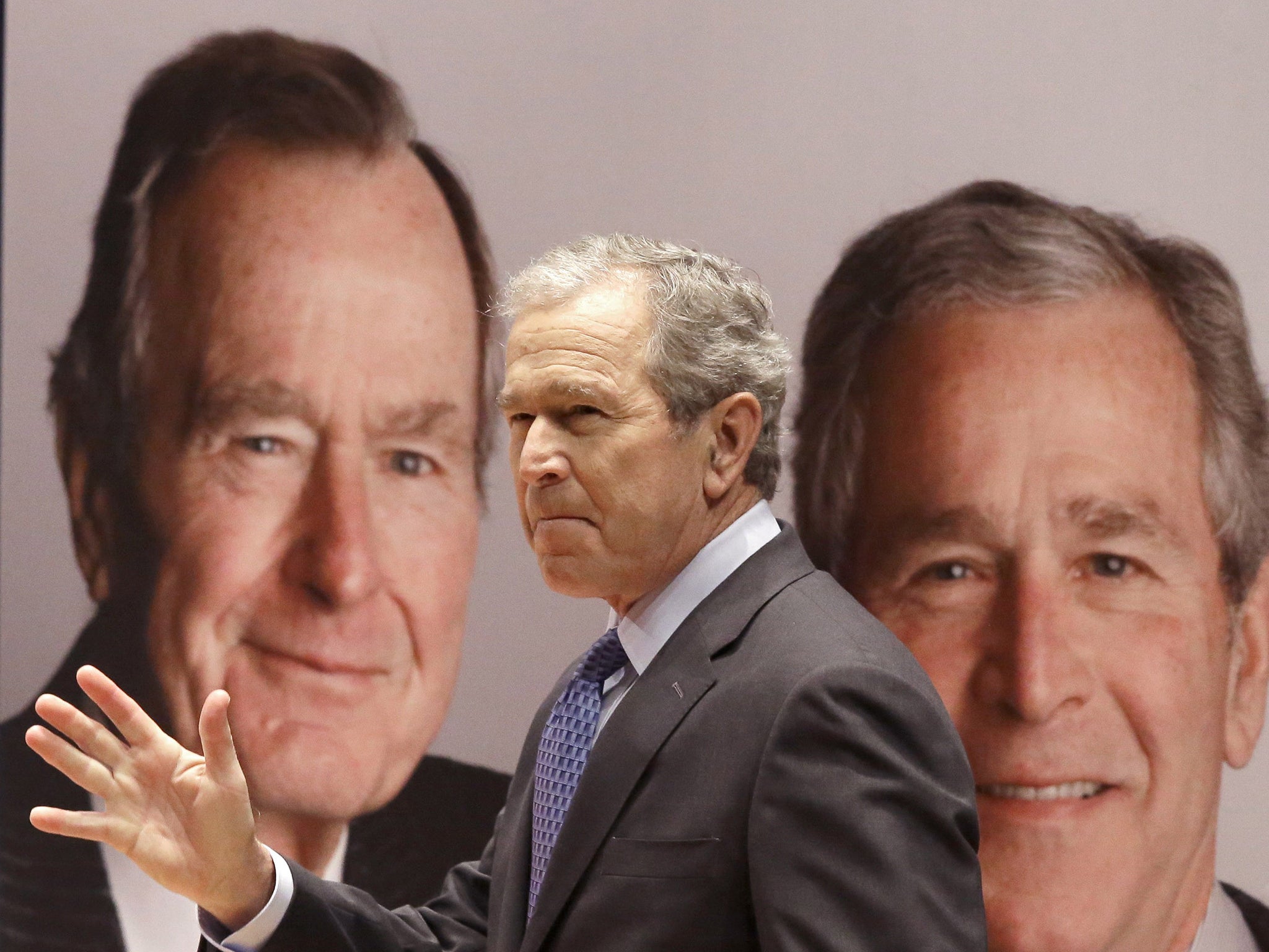 Former President George W. Bush passes a portrait of himself and his father former President George H.W. Bush