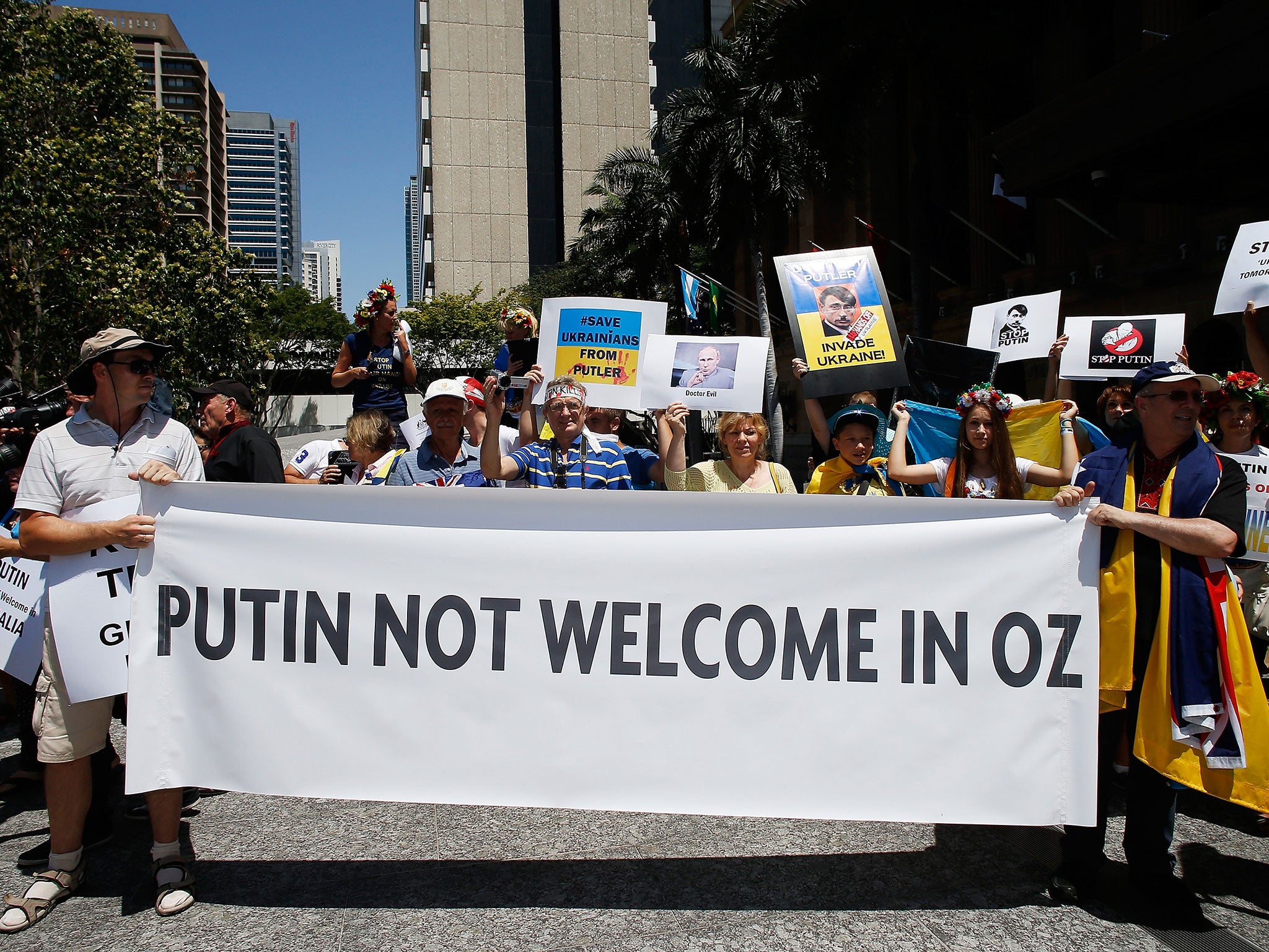 A woman holds banners against Russian President Vladimir Putin during a protest outside the G20 summit