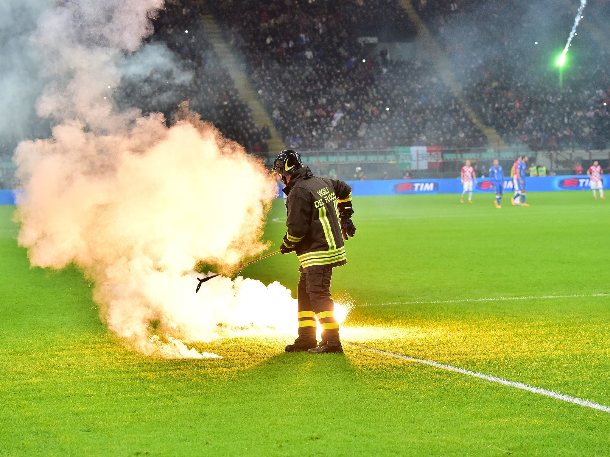 A fireman puts out one of the many flares thrown onto the San Siro pitch