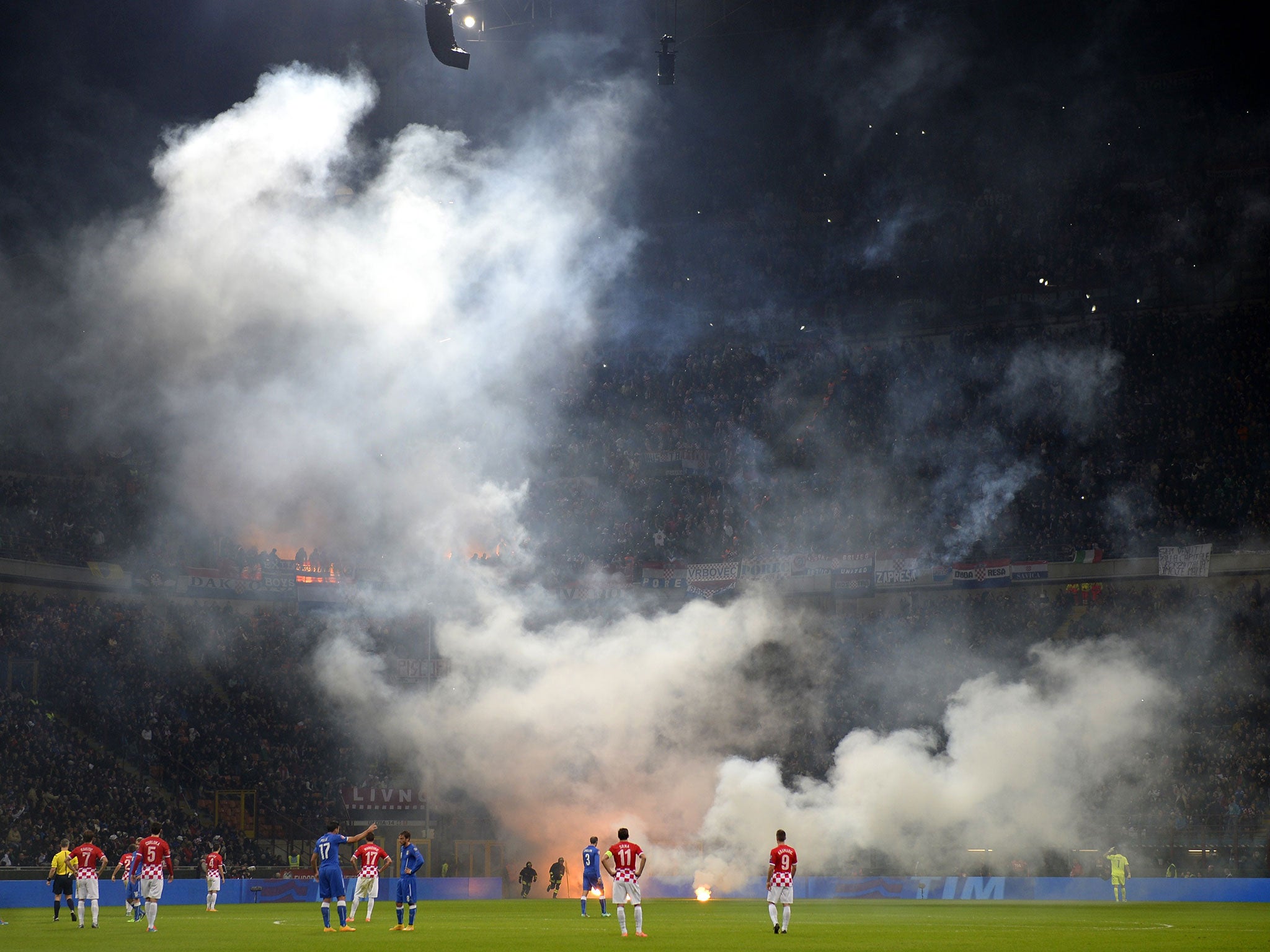 The San Siro pitch is engulfed in smoke from flares thrown onto the pitch